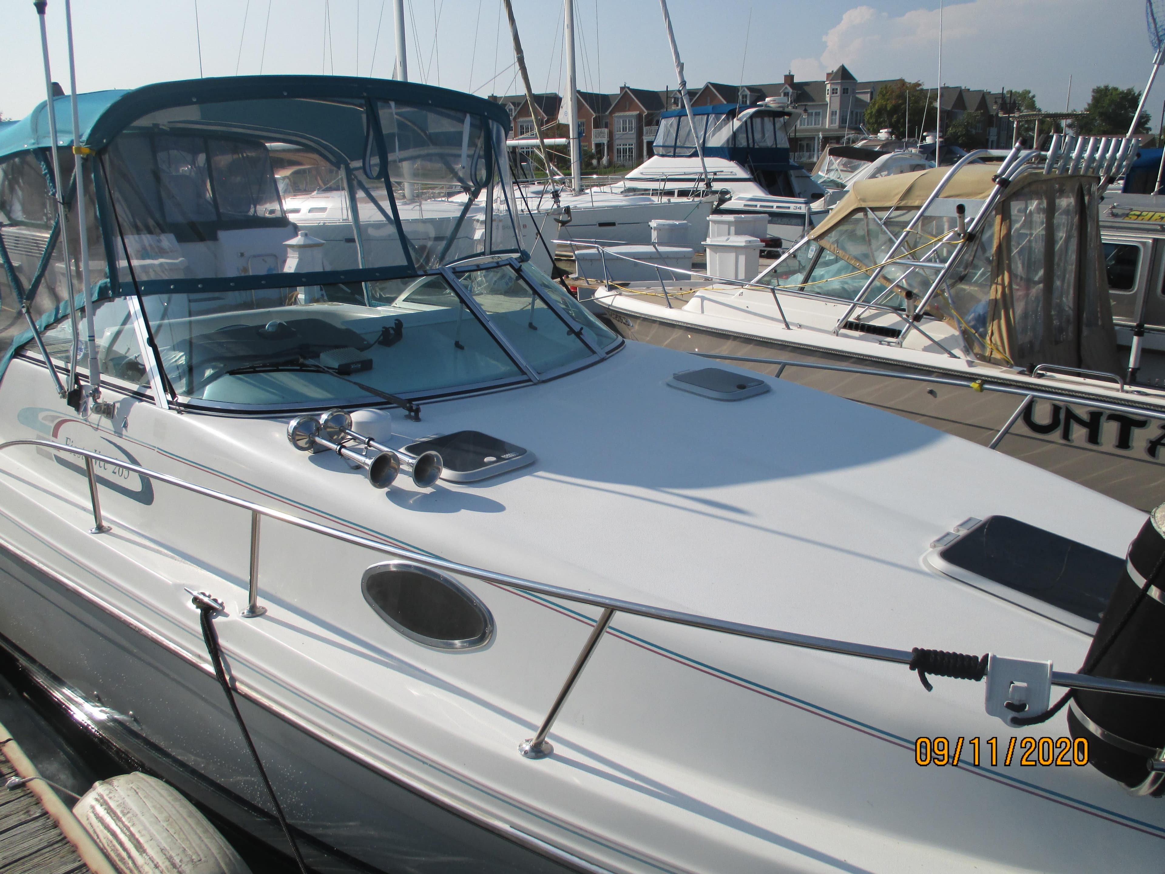 1994 Rinker Fiesta Vee 265 boat docked at marina with blue canopy.