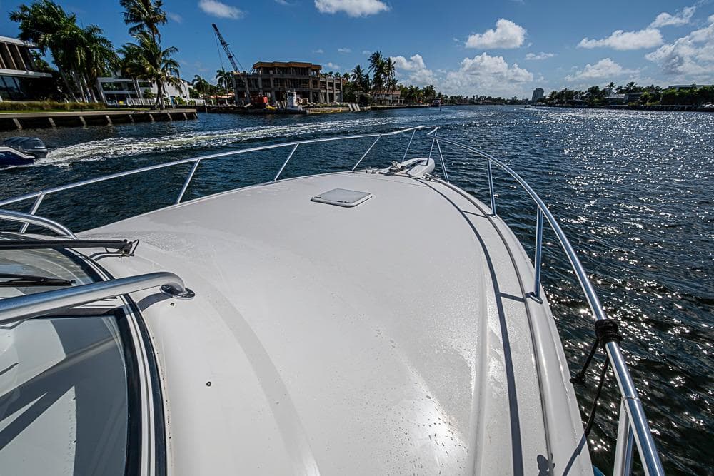 2021 Viking 38 Open yacht cruising on a sunny waterway with palm trees.