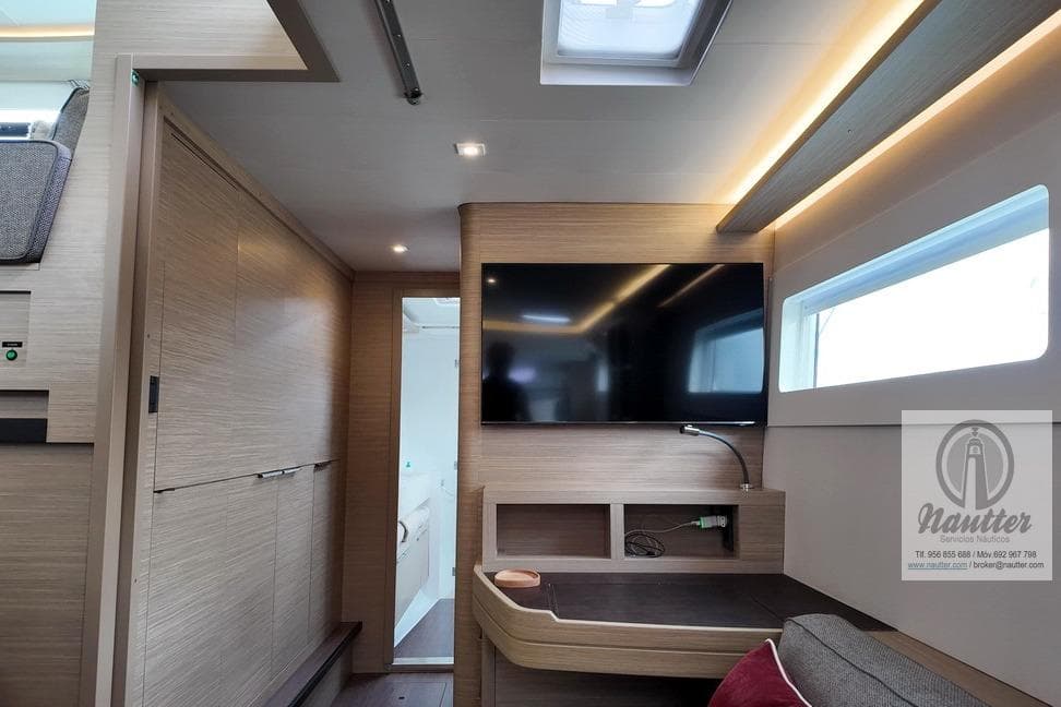 Modern interior of 2023 Lagoon 46 yacht with TV and sleek wood finishes.