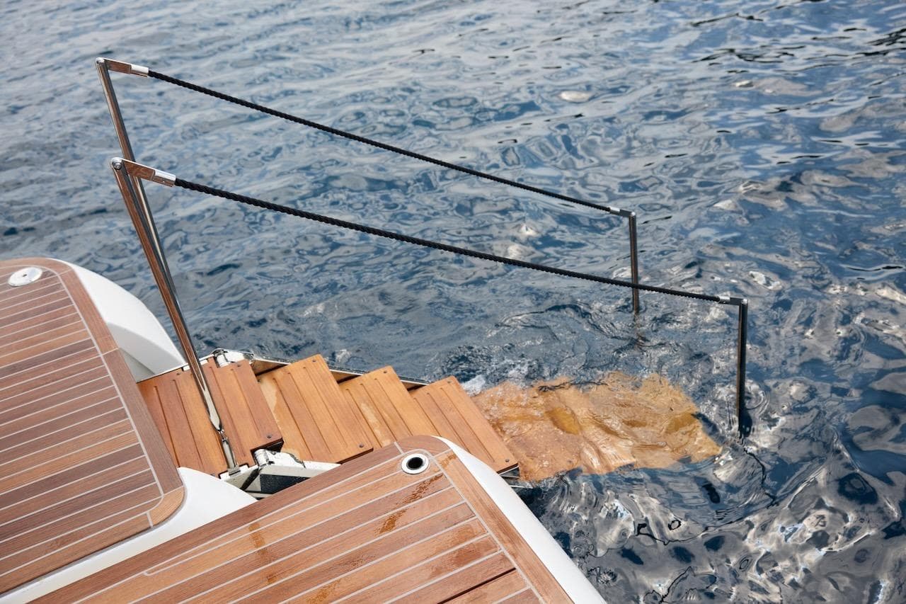 Luxury yacht Prestige M7 2025 with wooden swim platform and steps into water.