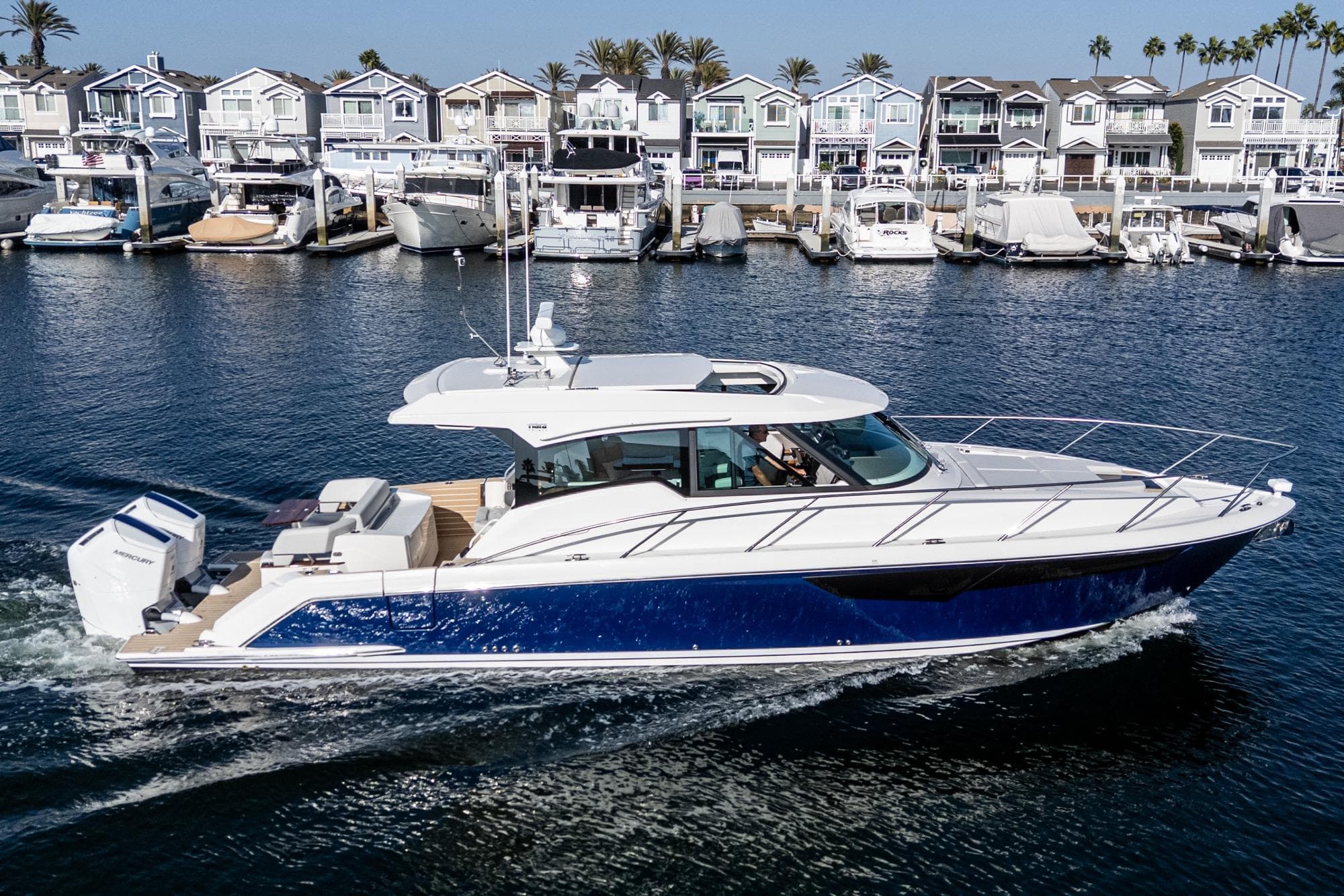 2026 Tiara Yachts 43LE cruising in a marina with waterfront homes in the background.