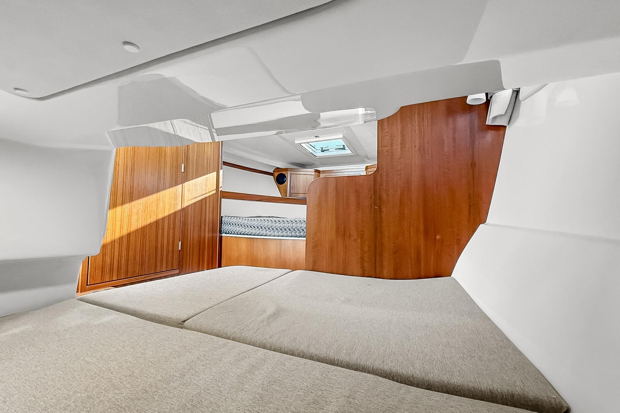 Interior cabin of 2021 Aquador 28 HT boat with wooden accents and bedding.