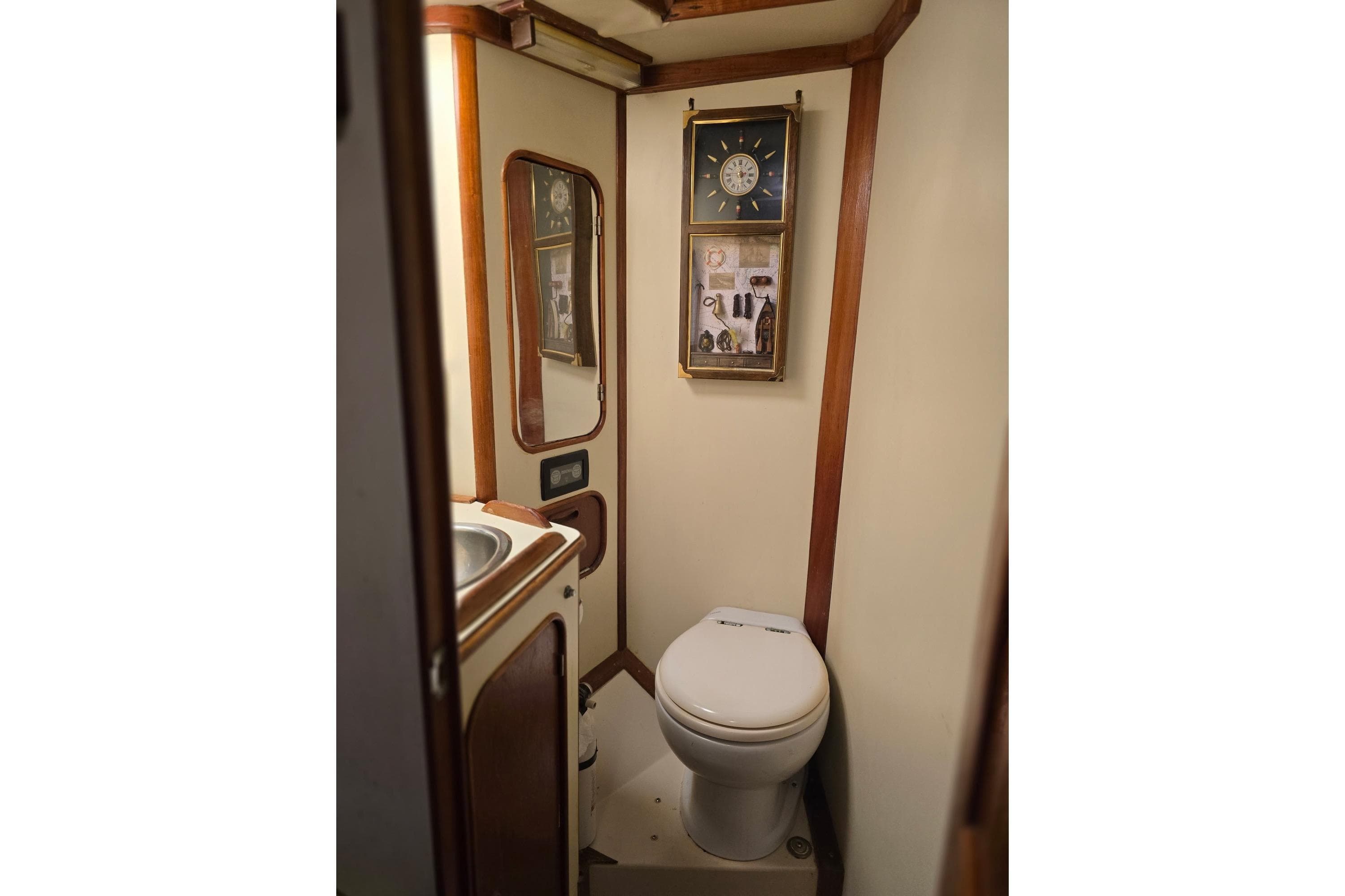 Compact bathroom in a 1982 Irwin 52 yacht, featuring a toilet, sink, and nautical decor.