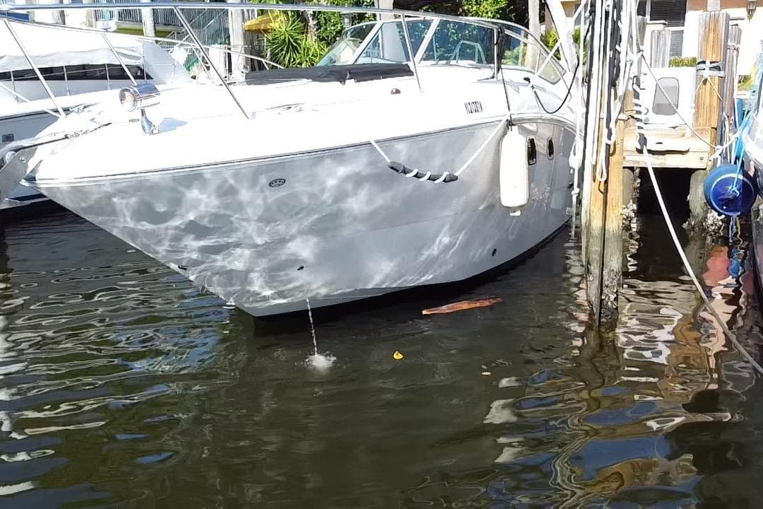 2012 Sea Ray 330 Sundancer docked in a marina, reflecting sunlight on water.