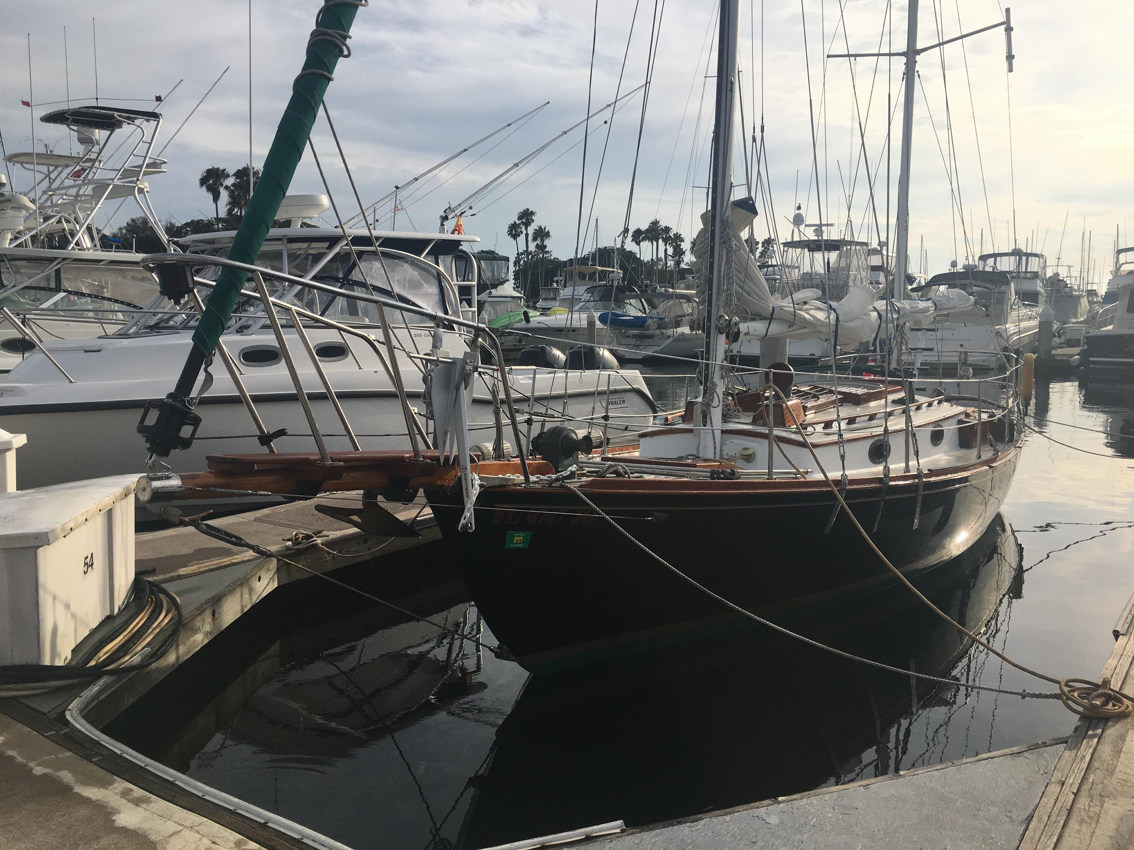 1988 Custom Aft Cockpit sailboat docked in a marina, surrounded by other boats.