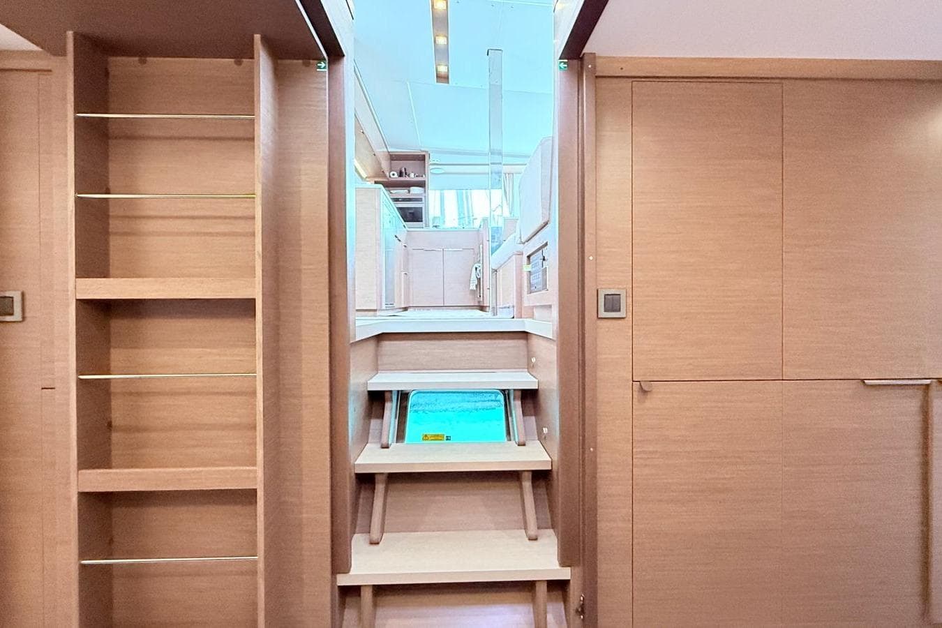 Interior of 2020 Lagoon 46 yacht with wooden stairs and shelving.