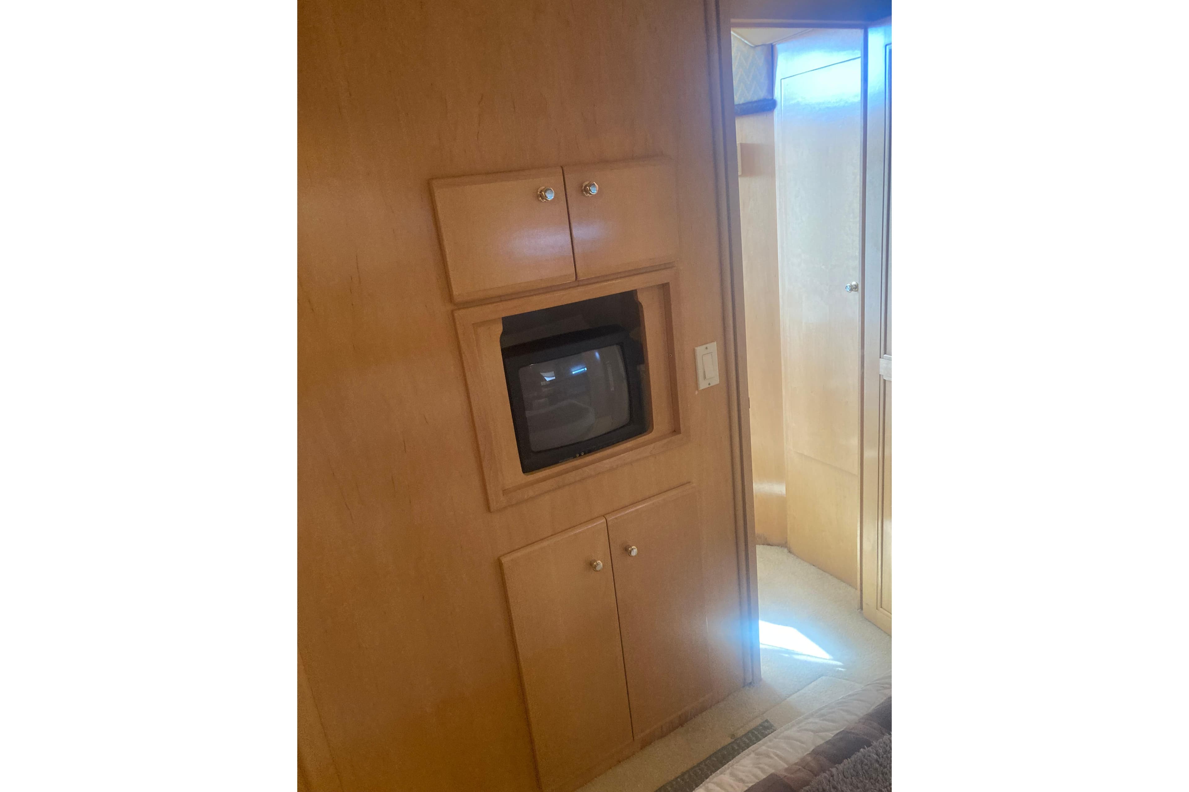 Interior of 2001 Carver 406 Aft Cabin Motor Yacht with built-in TV and wooden cabinetry.