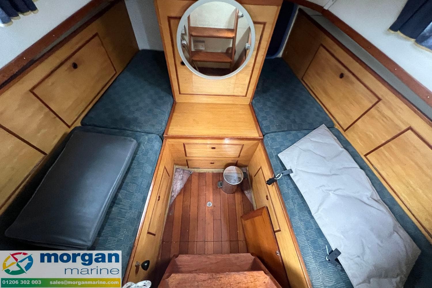 Interior of 1972 Barbary Ketch boat with wooden cabinetry and blue cushions.