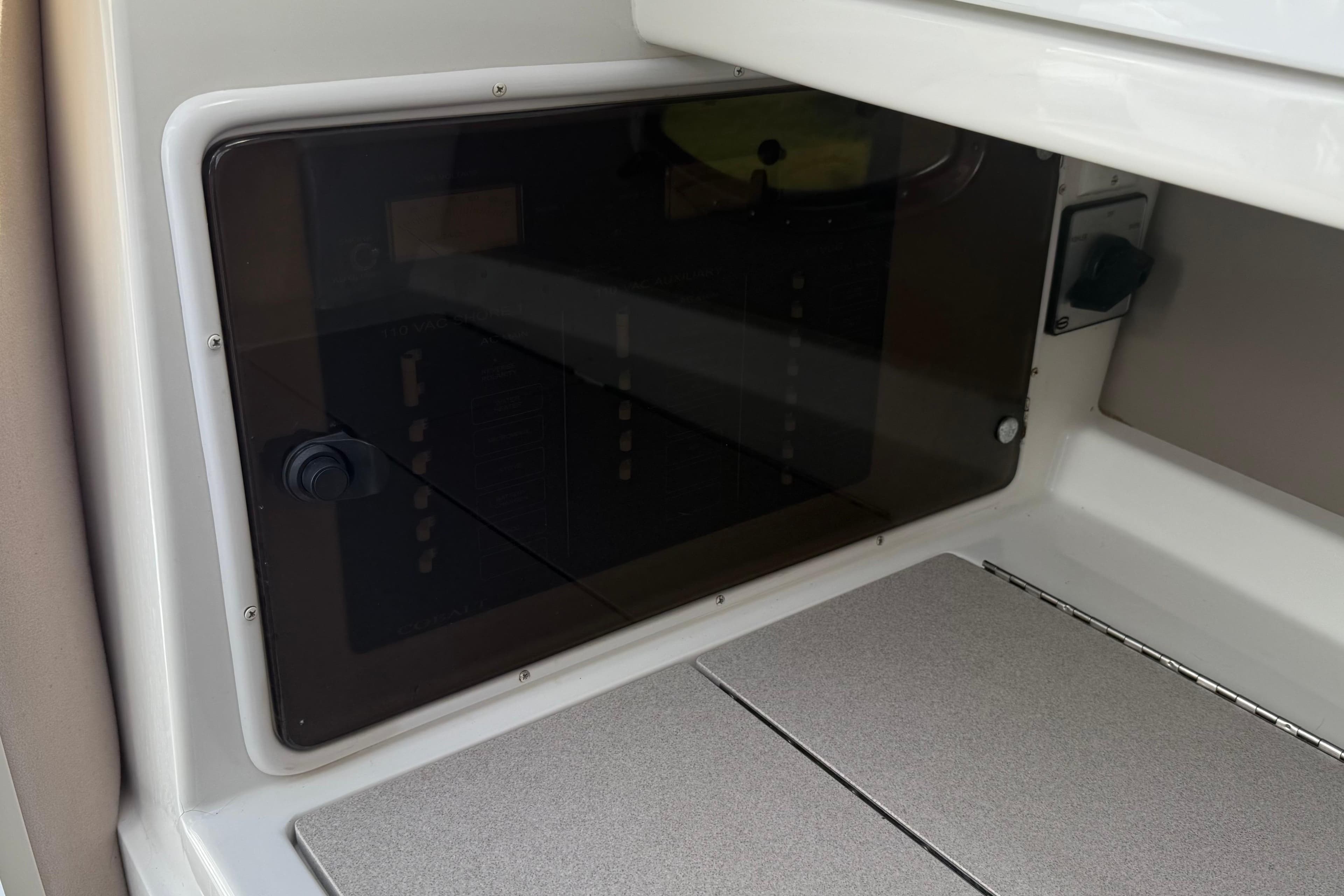 1999 Cobalt 293 interior storage compartment with transparent door and control panel.