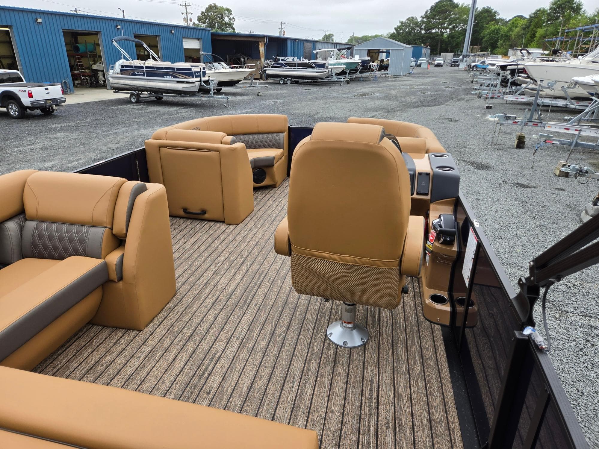 2026 Harris Cruiser 210 pontoon boat interior with tan seating and wood-style flooring.