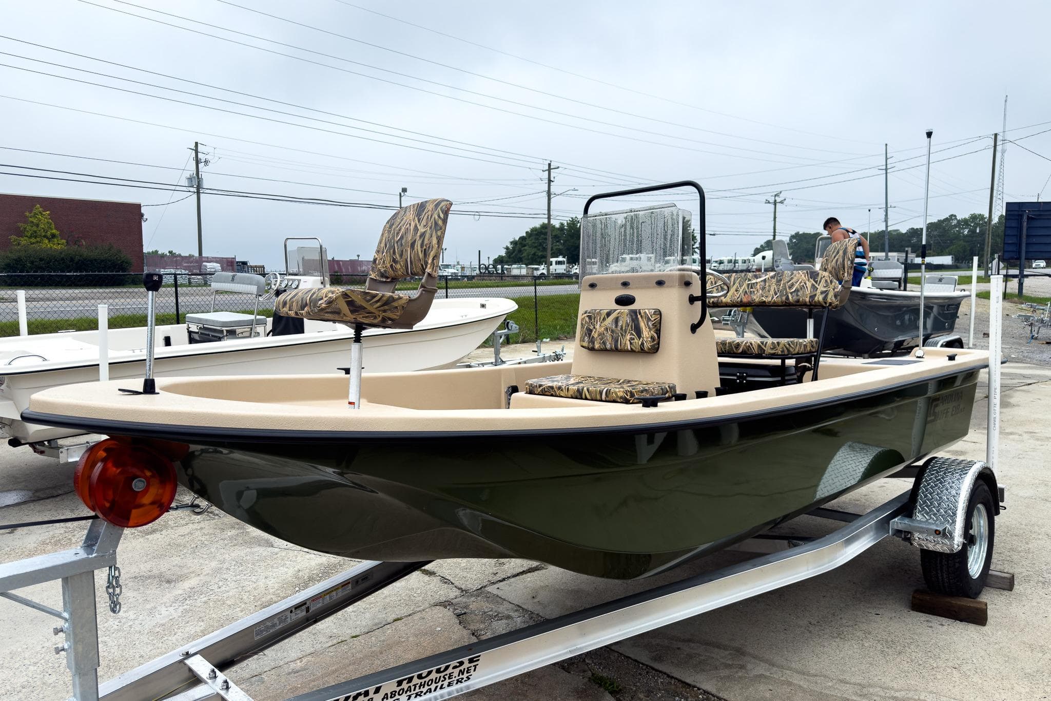 2026 Carolina Skiff E18 JVX CC Sportsman boat on trailer, camo seats, outdoor setting.