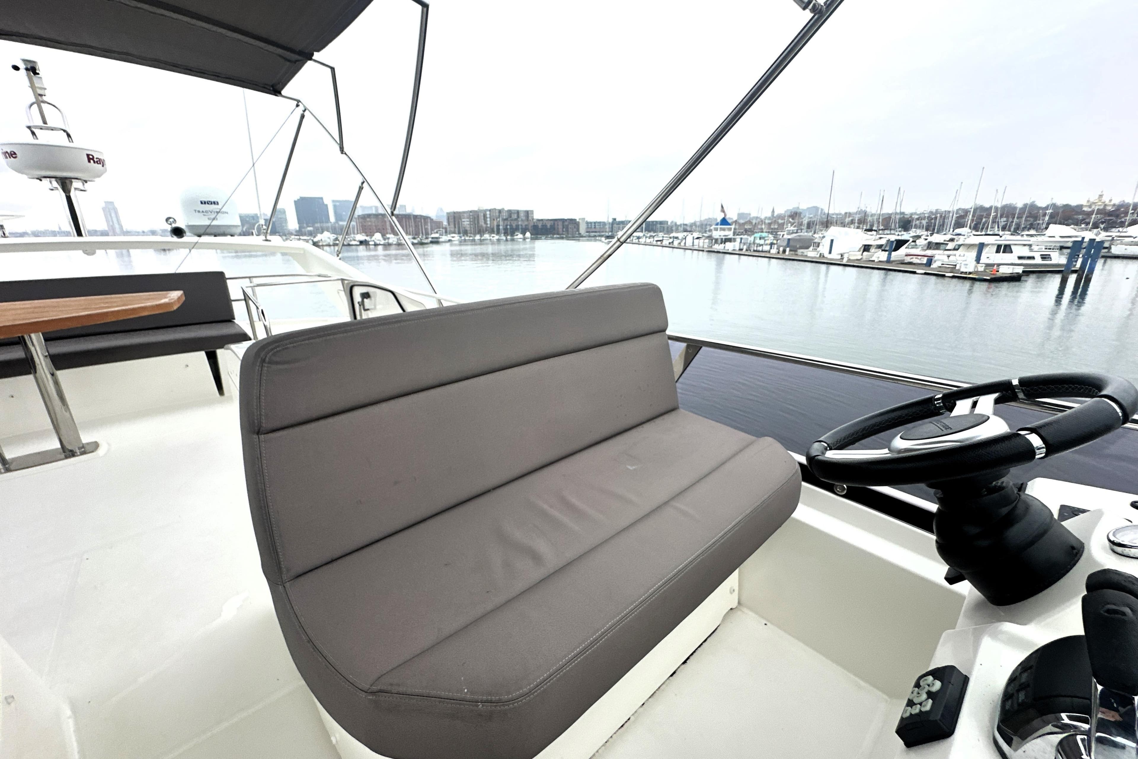 Flybridge of 2017 Prestige 500 yacht with helm and seating, overlooking marina.