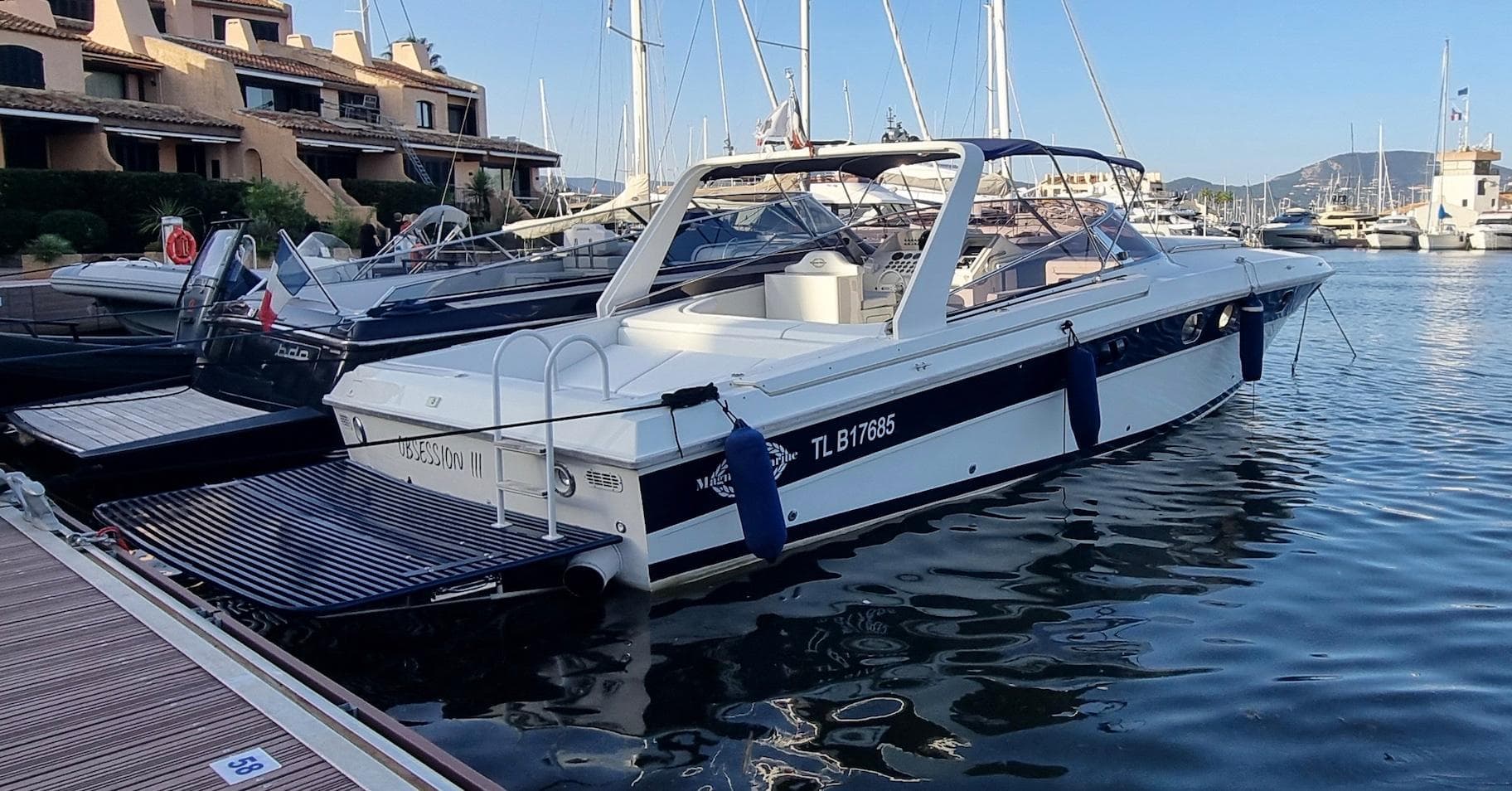 1990 Magnum 40 boat docked in a marina, surrounded by other vessels and waterfront buildings.