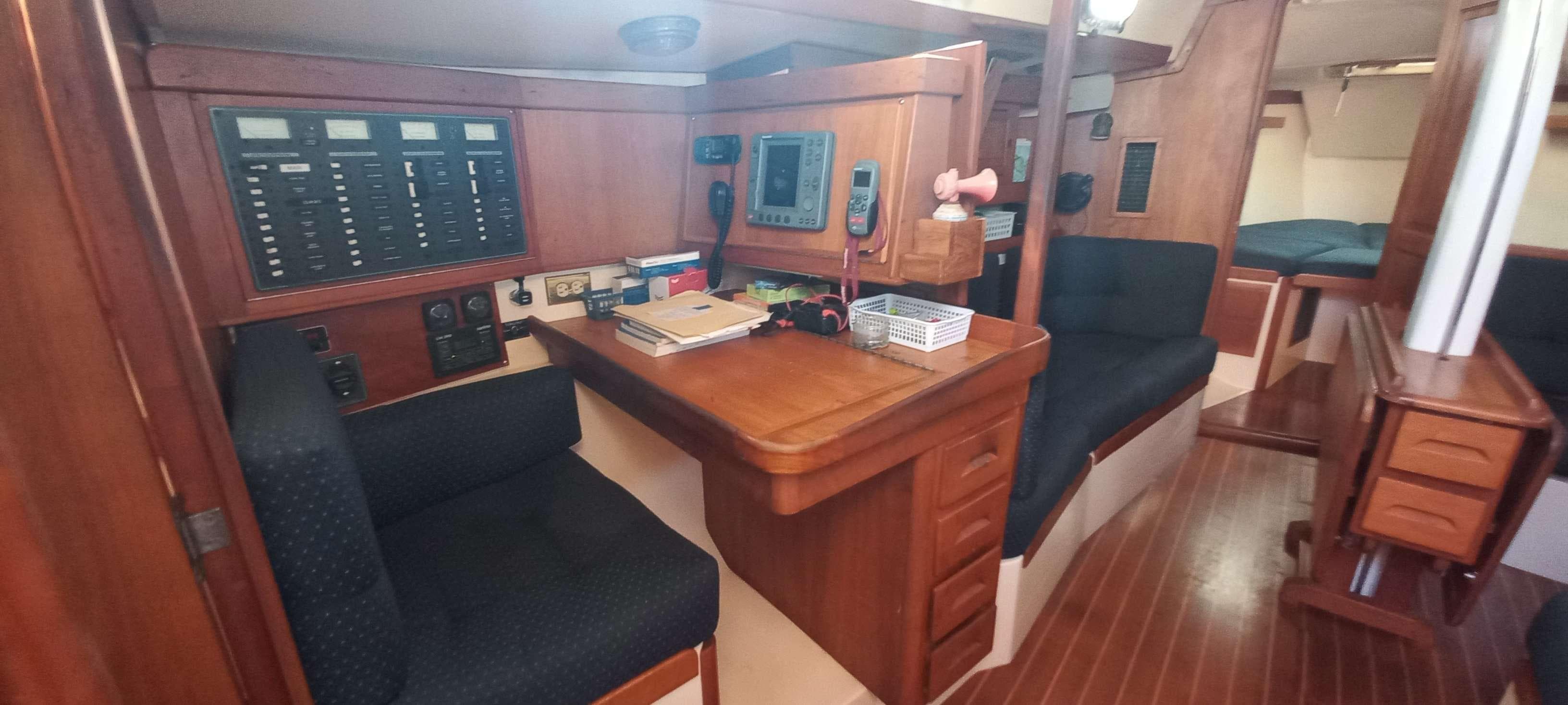 Navigation station inside a 2003 Tartan 3700 sailboat, featuring wood paneling and seating.