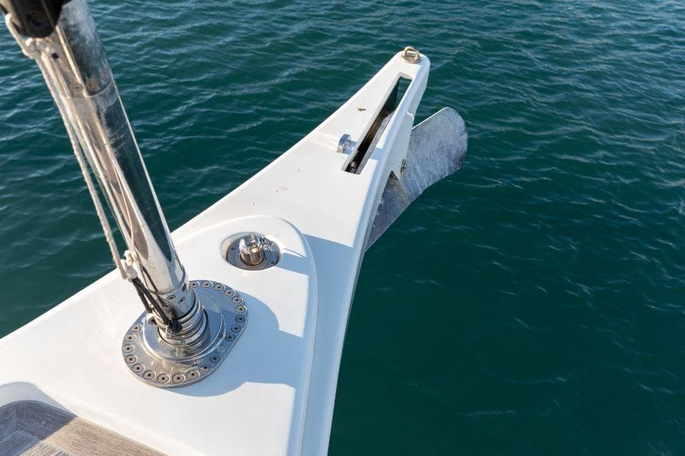 Bow of 2022 Solaris 64RS yacht with anchor over clear blue water.