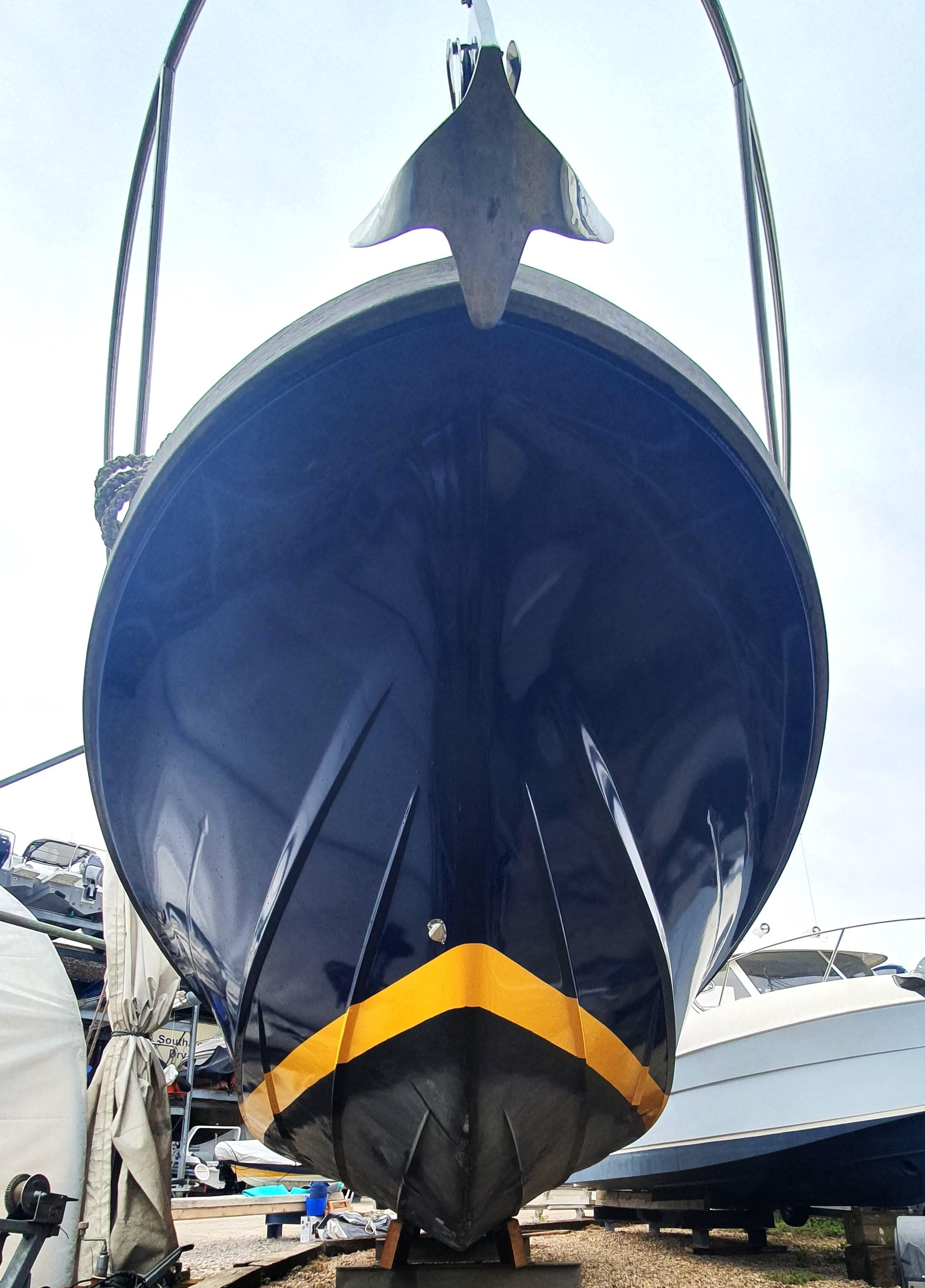 2006 Swordsman 30 boat with a sleek blue hull and yellow stripe, viewed from the front.