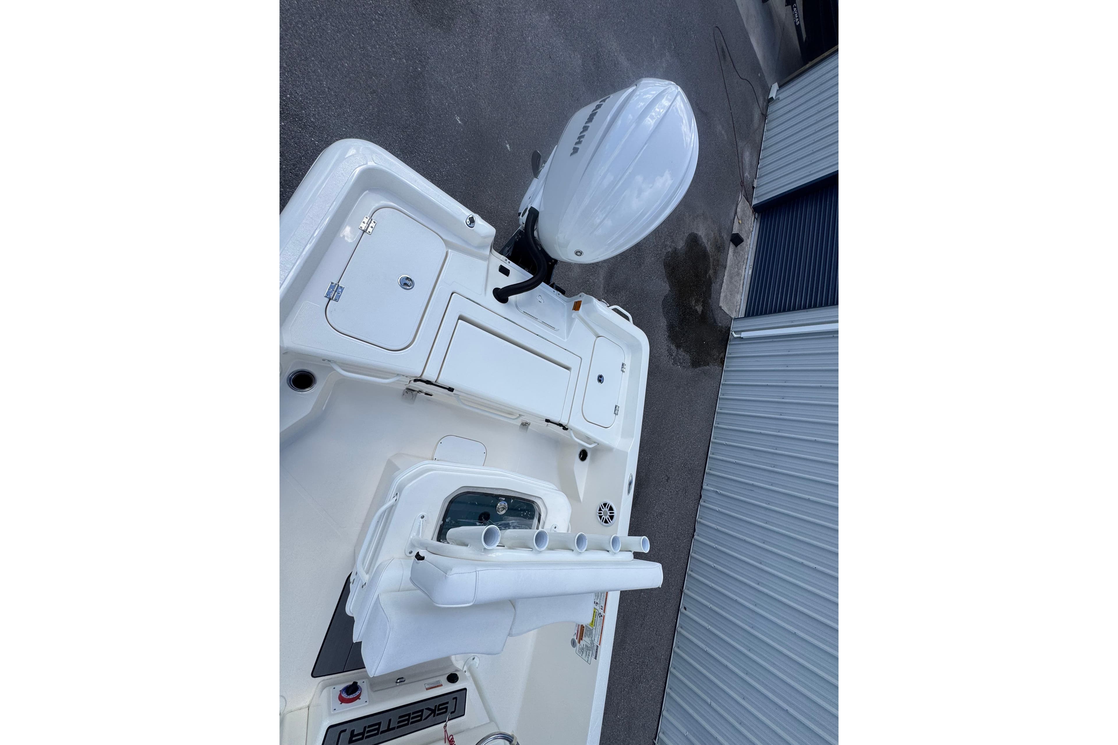 2026 Skeeter SX2350 boat deck with Yamaha outboard motor, docked near a metal building.