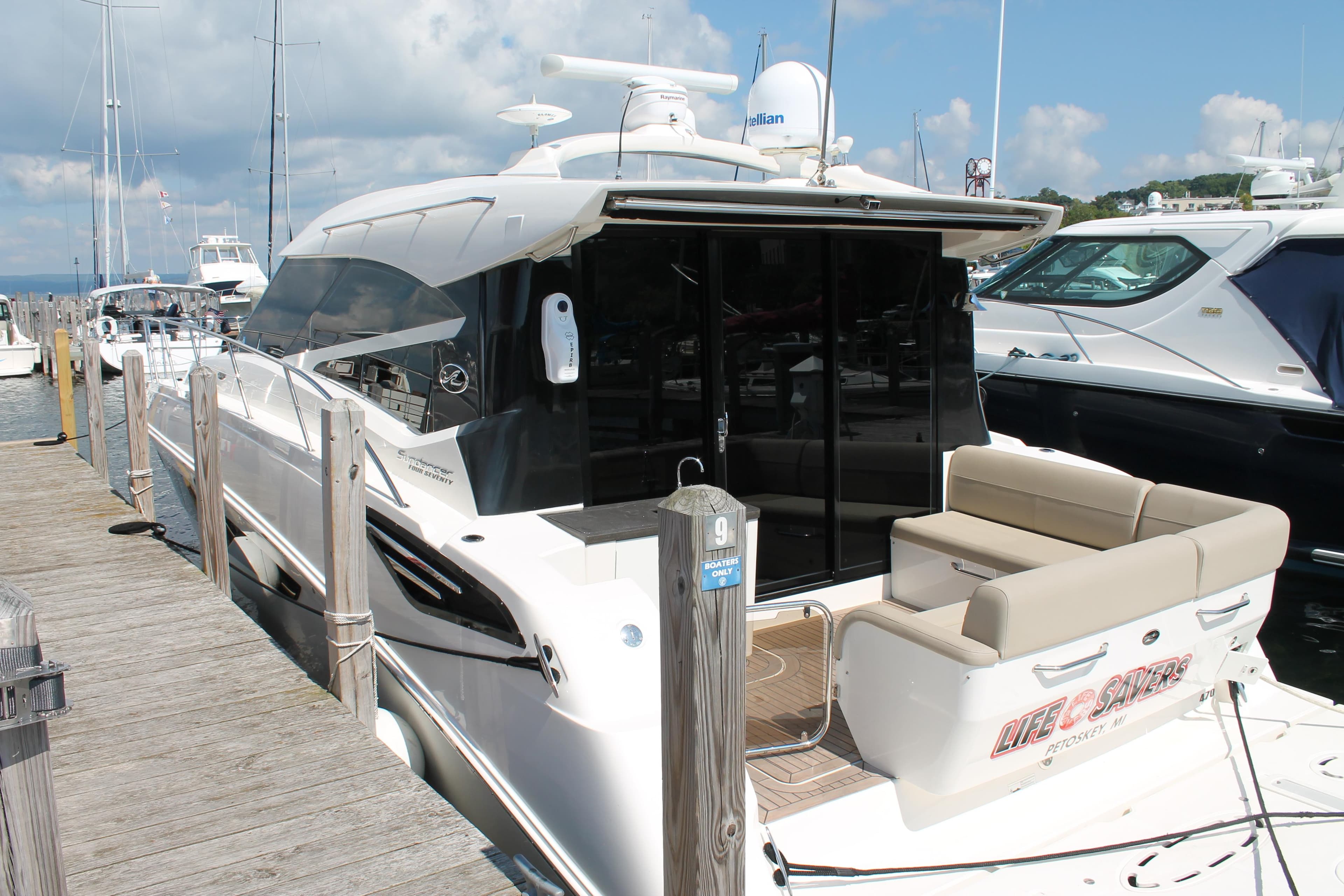 2015 Sea Ray 470 Sundancer yacht docked at marina under blue sky.