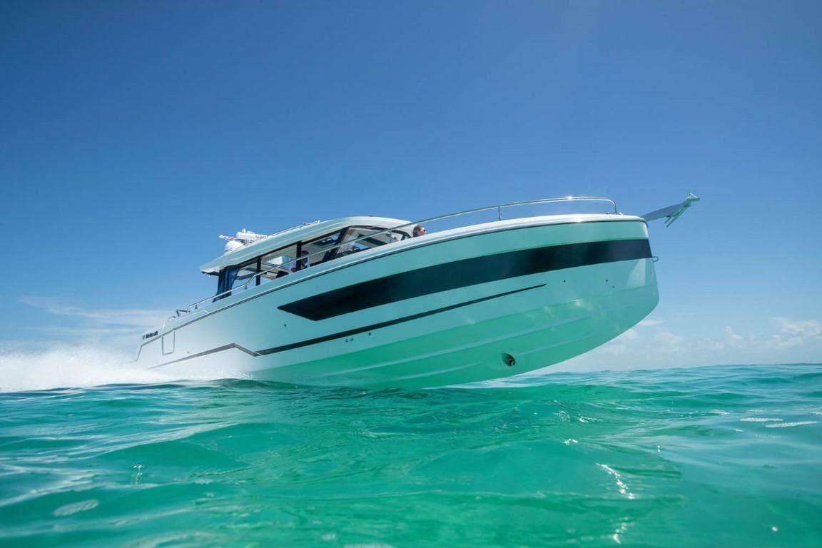 2025 Wellcraft 38 Explorer cruising on clear turquoise water under a bright blue sky.