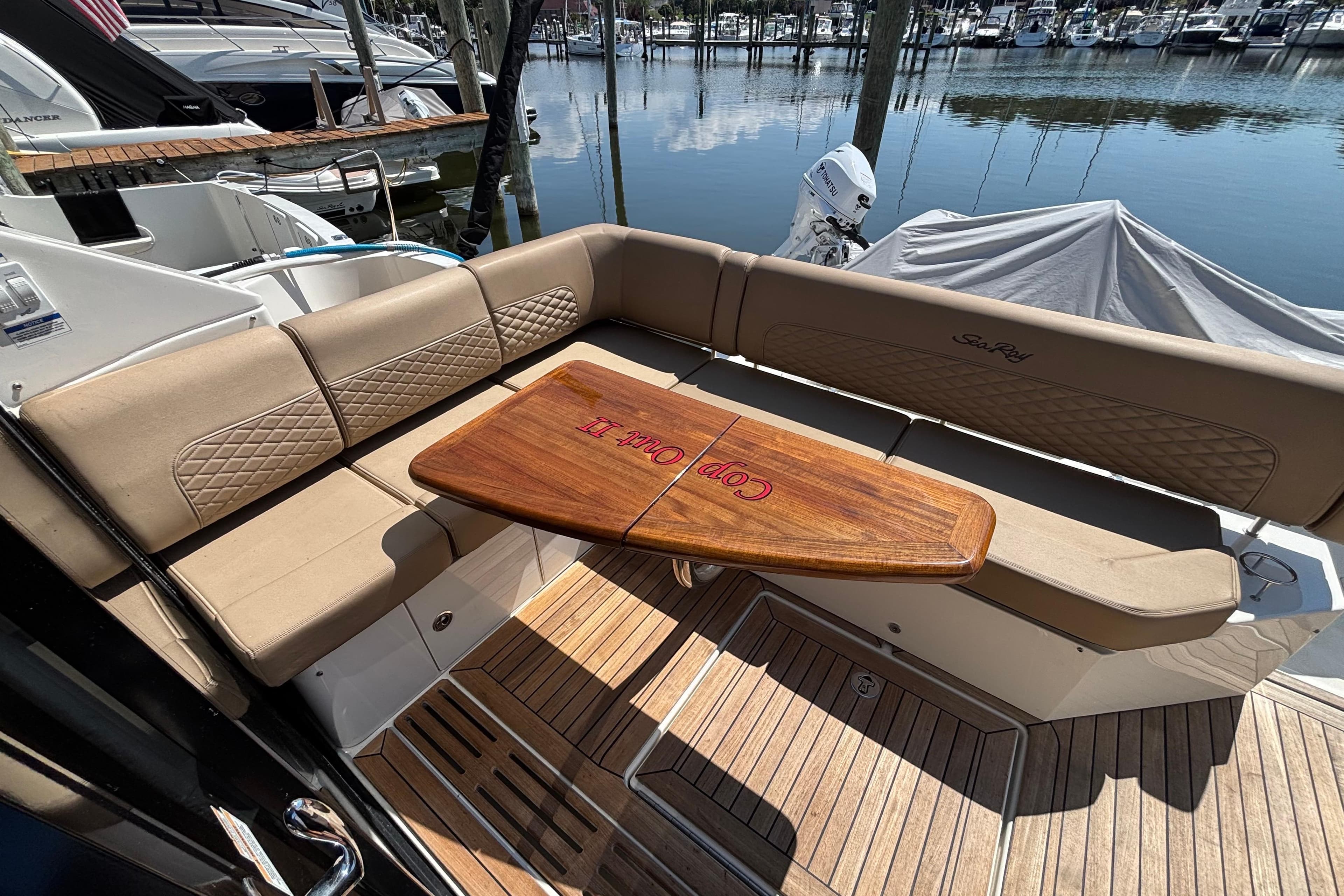 2018 Sea Ray Sundancer 460 yacht with elegant seating and wooden table at marina.