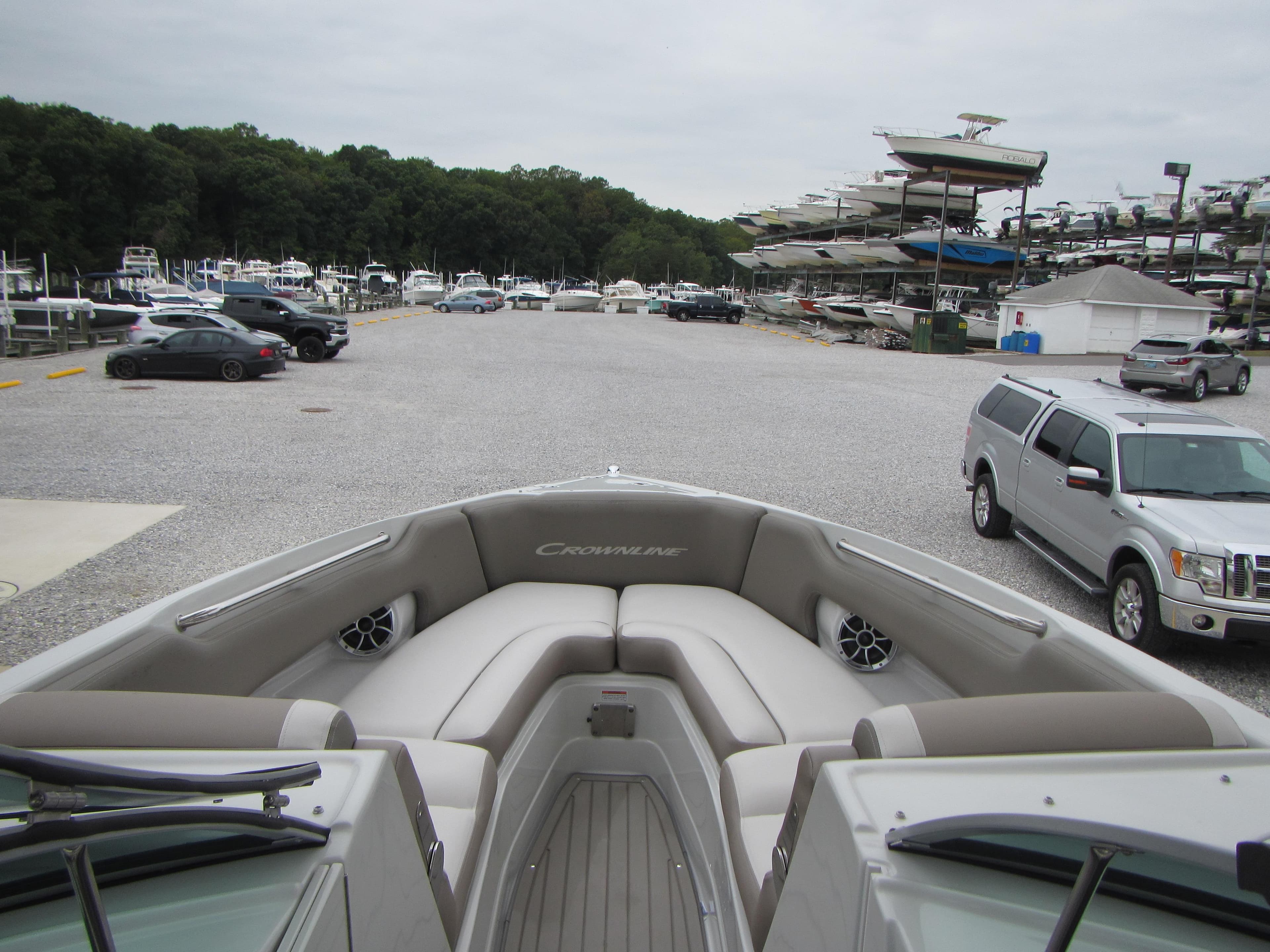 2023 Crownline 270 SS boat interior at marina with parked cars and boats.