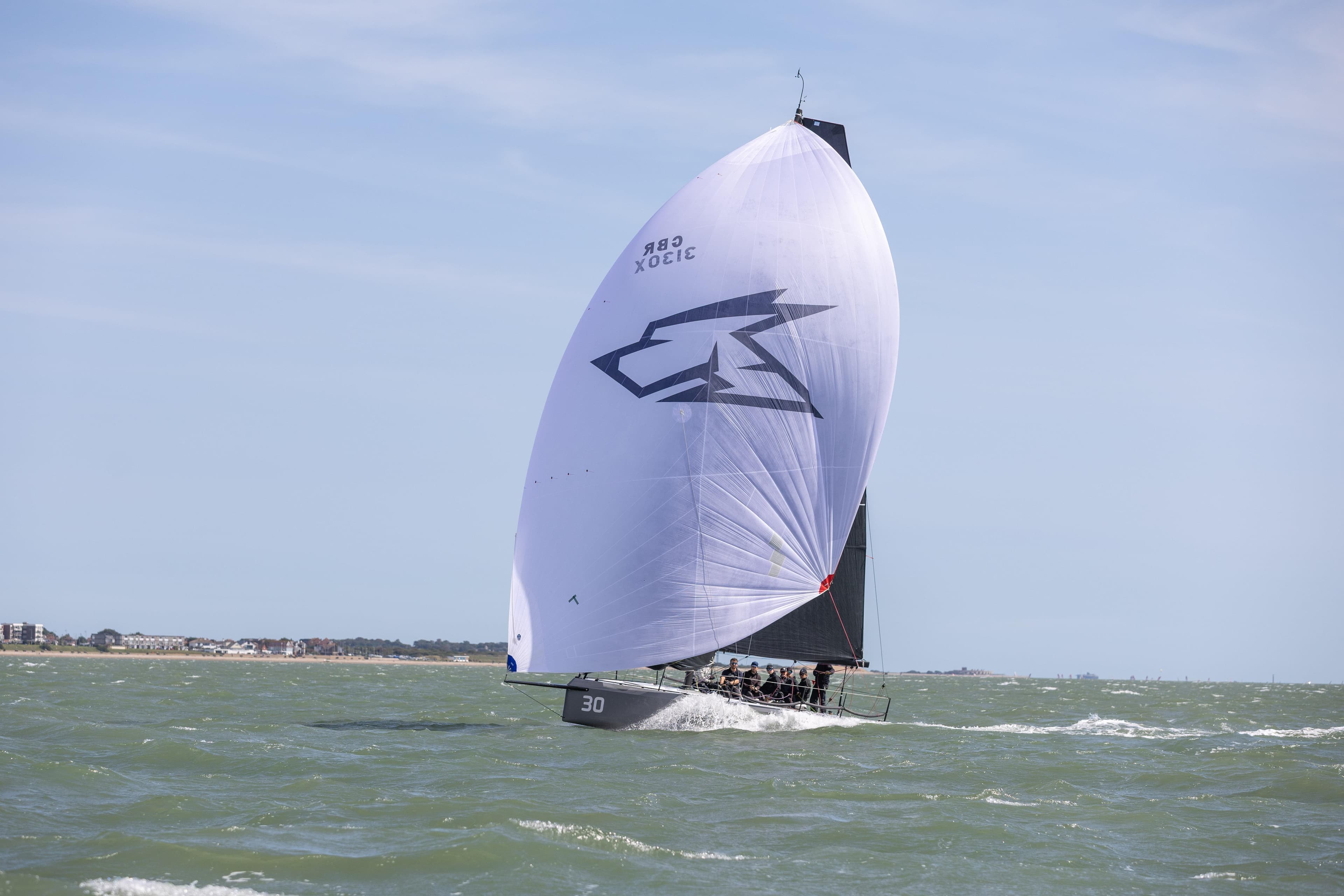 Sailing yacht One Design Cape31 2022 gliding on open sea with full spinnaker.