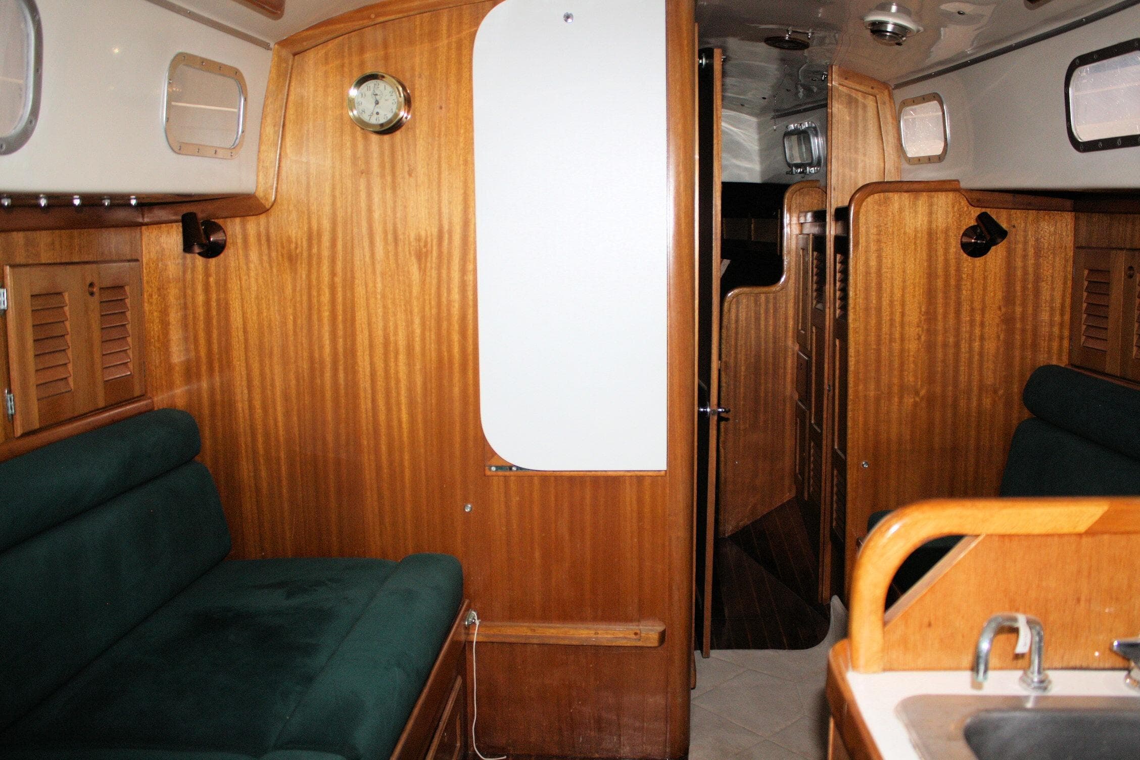 Interior of a 1981 Bristol 40 sailboat with wooden paneling and green seating.
