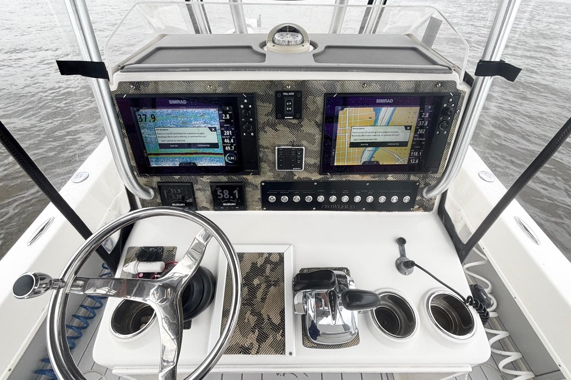 Control panel of a 2013 Prowler 25 boat with navigation screens and steering wheel.
