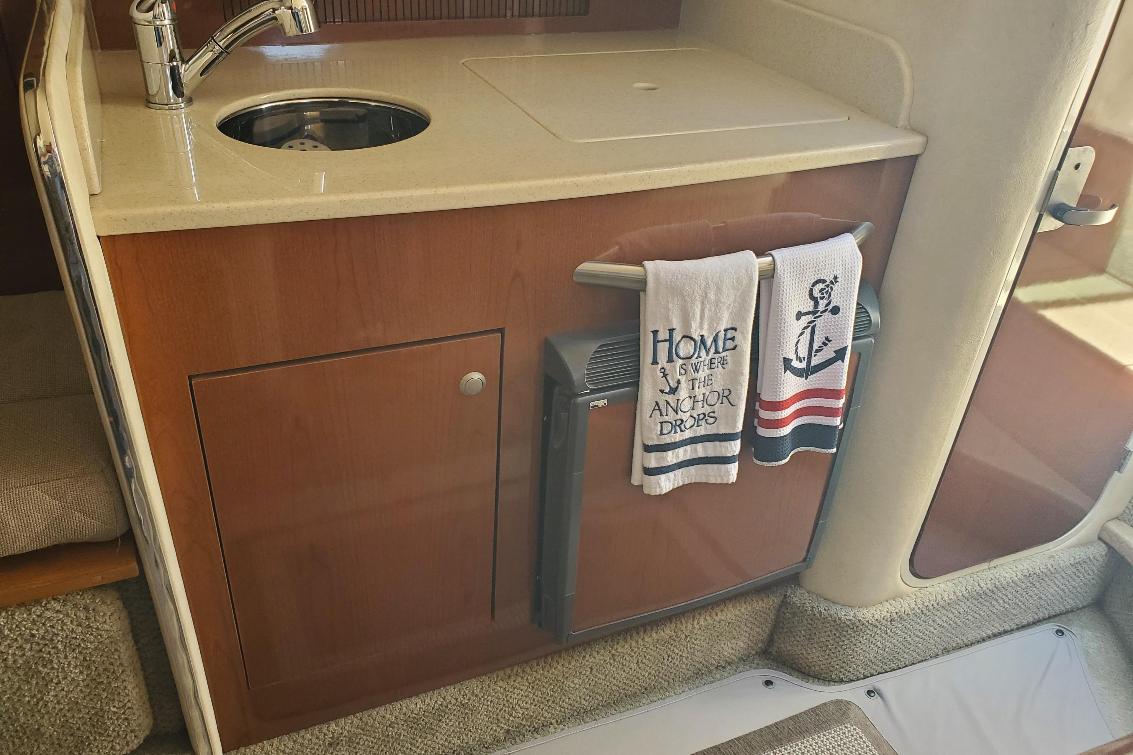 2008 Sea Ray Sundancer 280 interior with kitchenette, sink, and nautical-themed towels.
