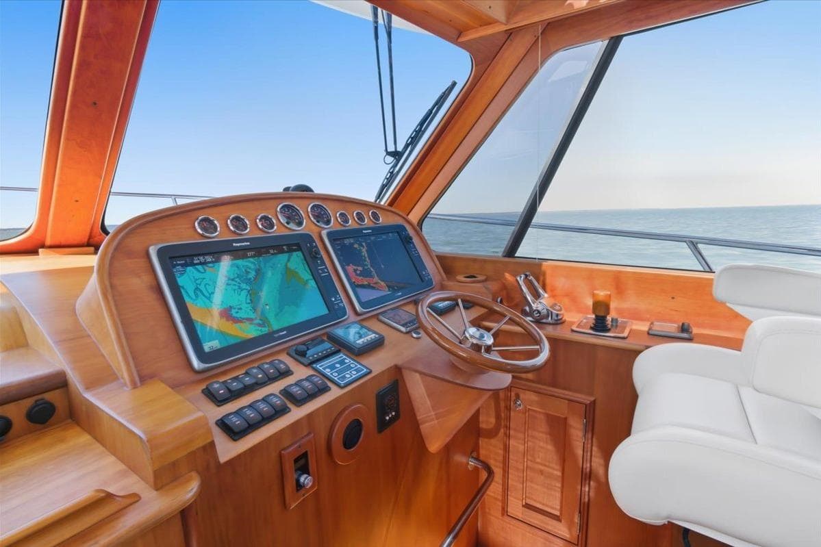 Helm of 2015 Hinckley Talaria 43 yacht with navigation screens and wooden dashboard.