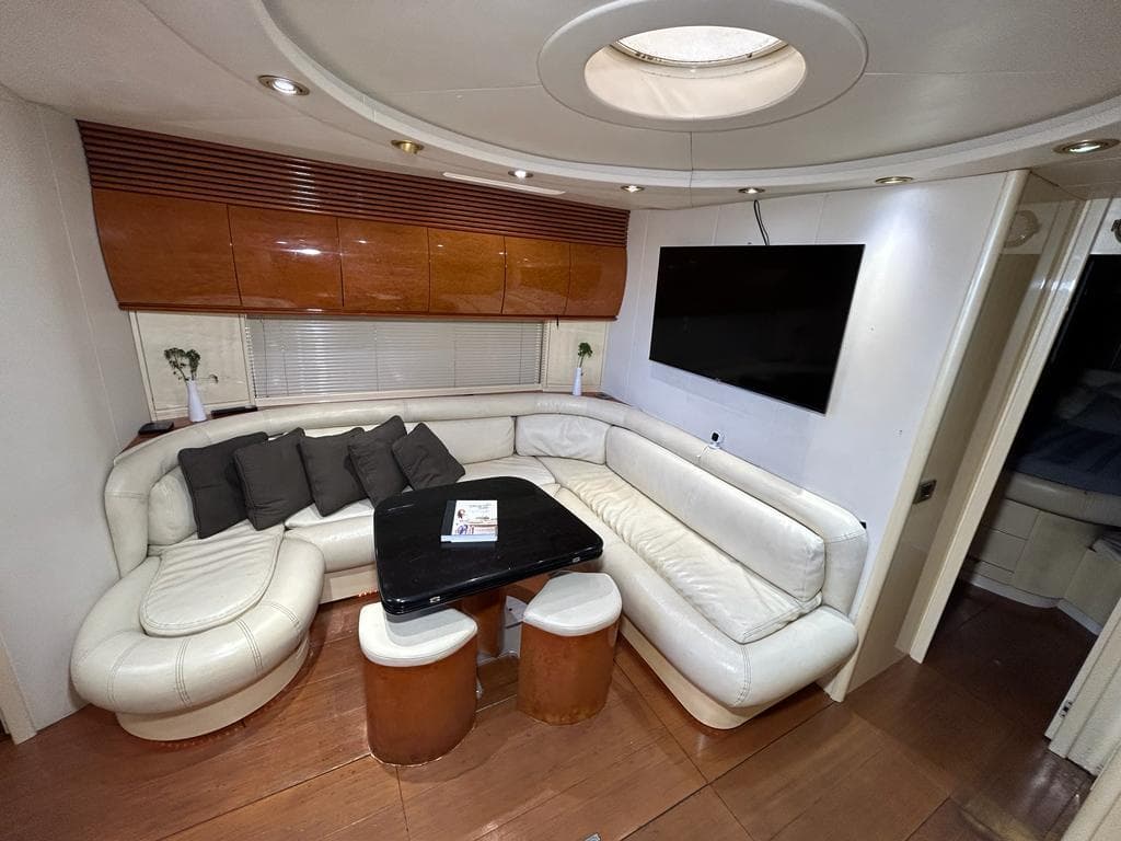 Luxurious interior of a 1999 Pershing 54 yacht with white leather seating and a flat-screen TV.