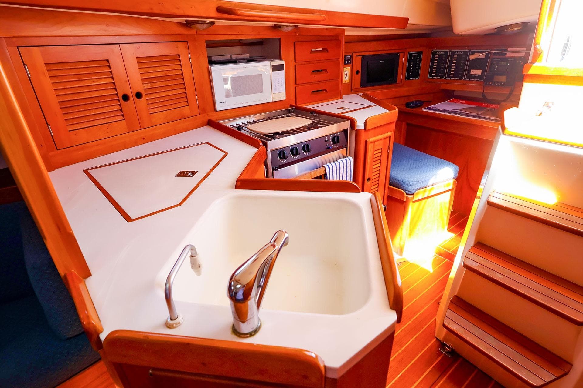 Interior of a 1999 Tartan 3500 yacht featuring a compact kitchen with wooden cabinetry.