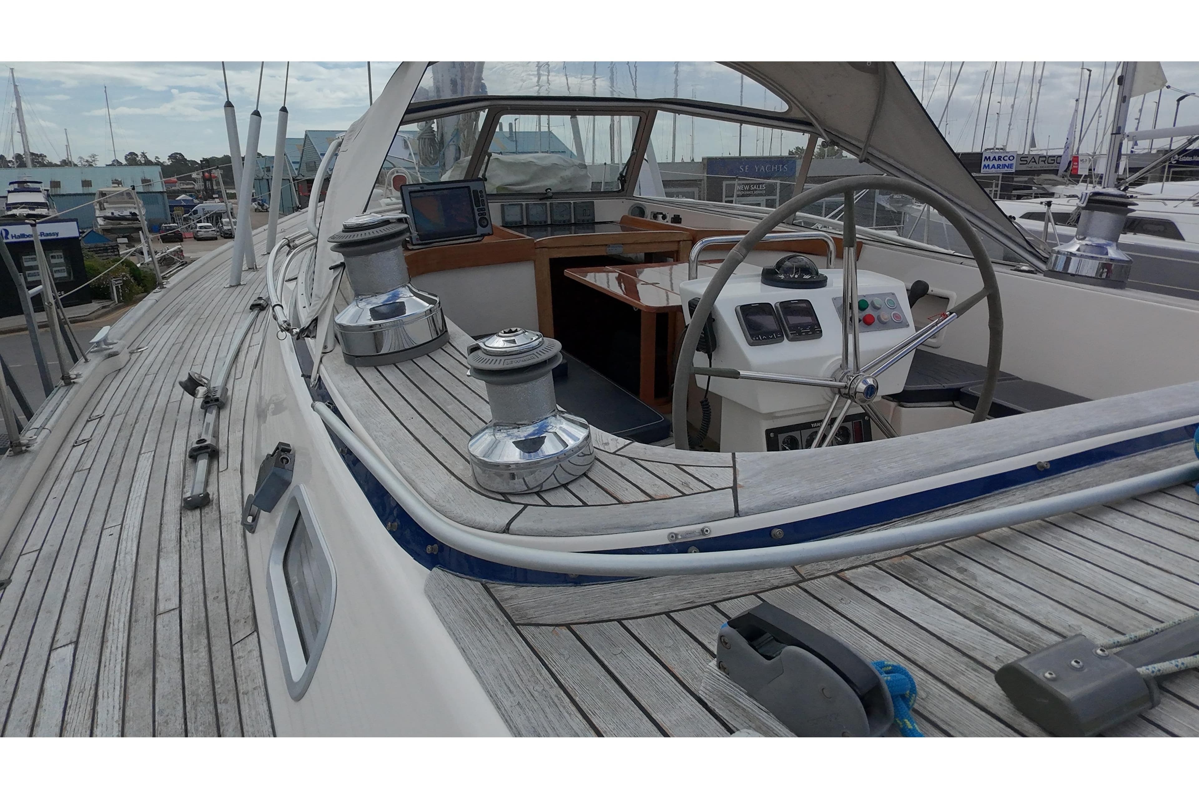 Deck view of a 2000 Hallberg-Rassy 46 sailboat, featuring steering wheel and winches.