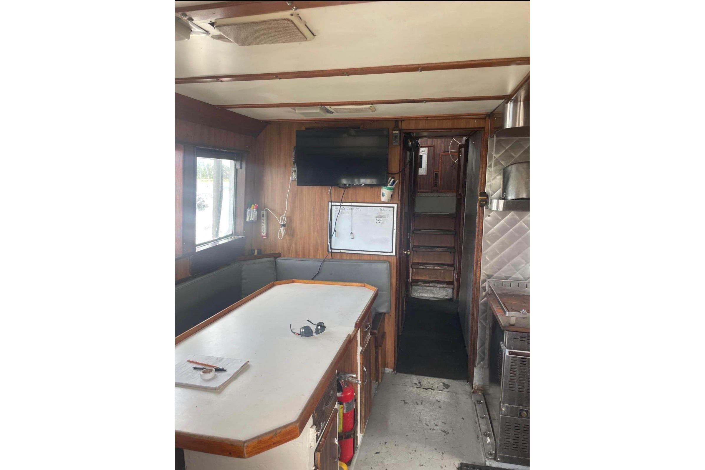 1974 Frostad Commercial Fishing boat interior with table, TV, and stairs.