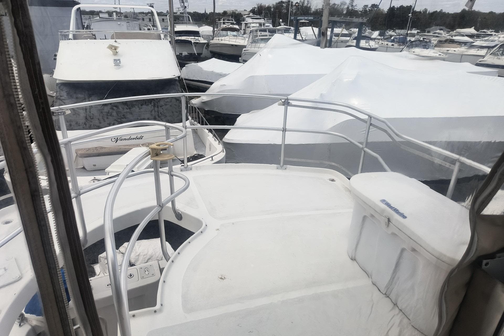 Mainship 390 Trawler 2000 docked among covered boats at a marina.