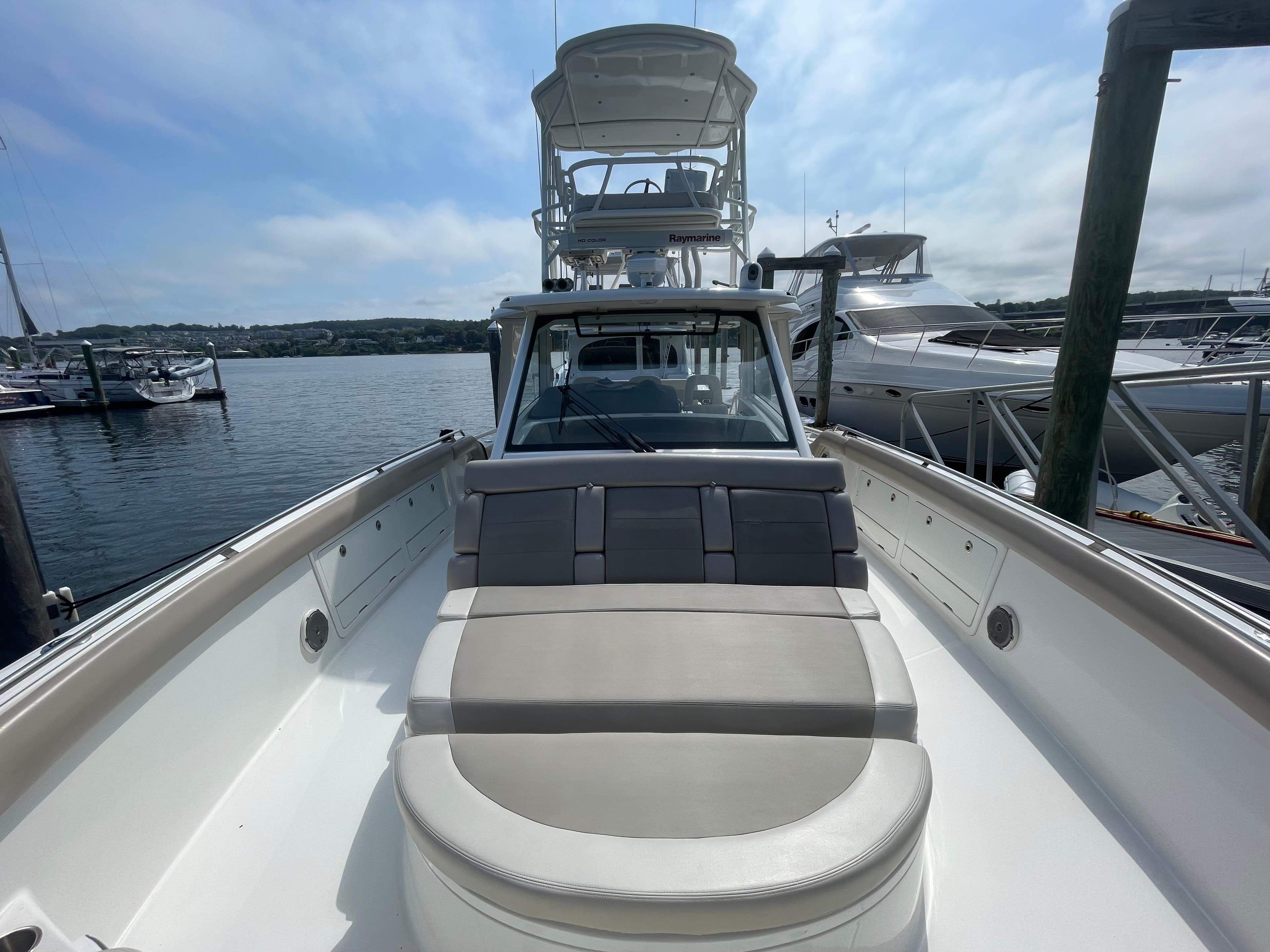 2017 Boston Whaler 420 Outrage boat docked at marina, featuring spacious seating and clear skies.
