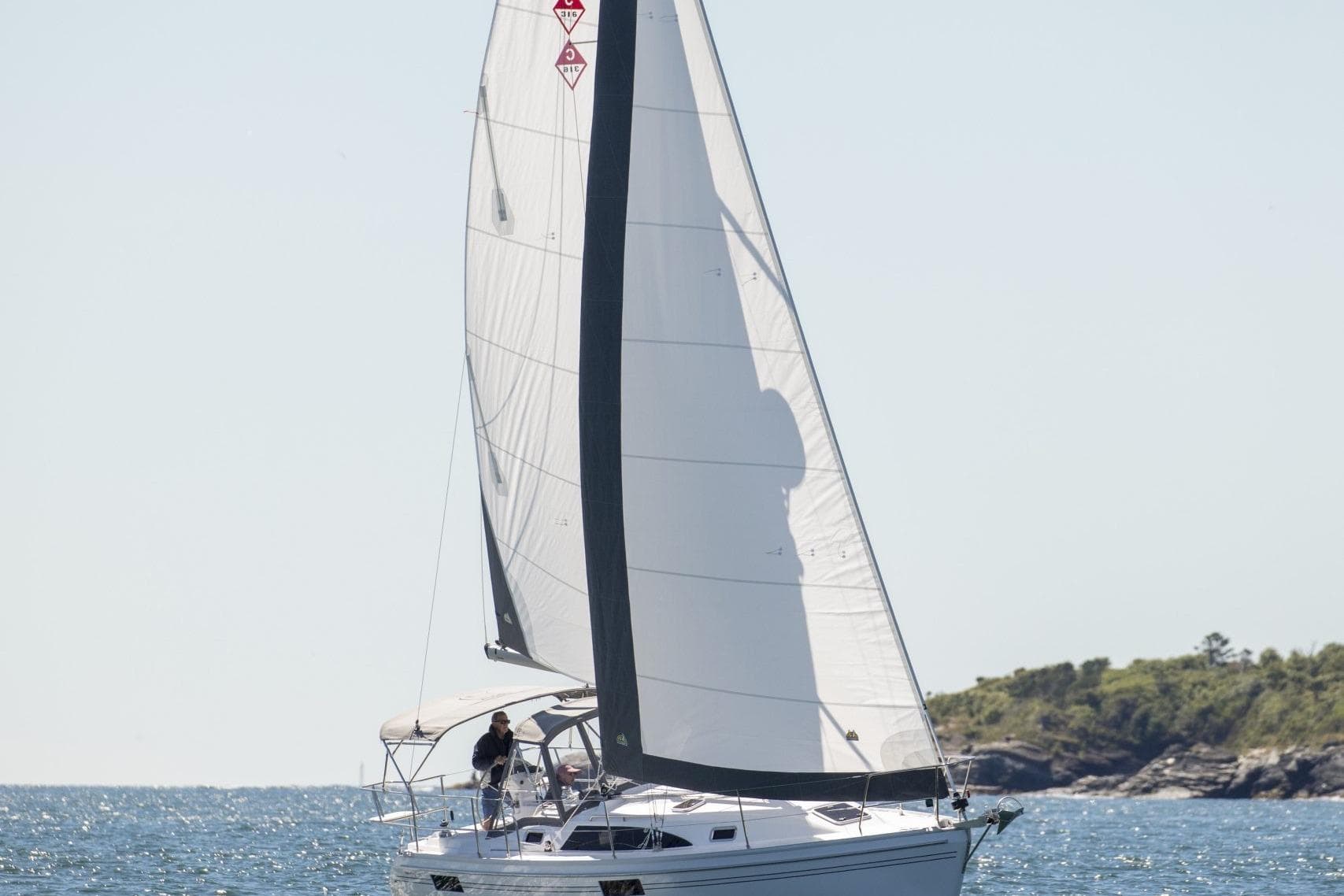Sailboat Catalina 316 (2026) cruising on open water near a rocky shoreline.