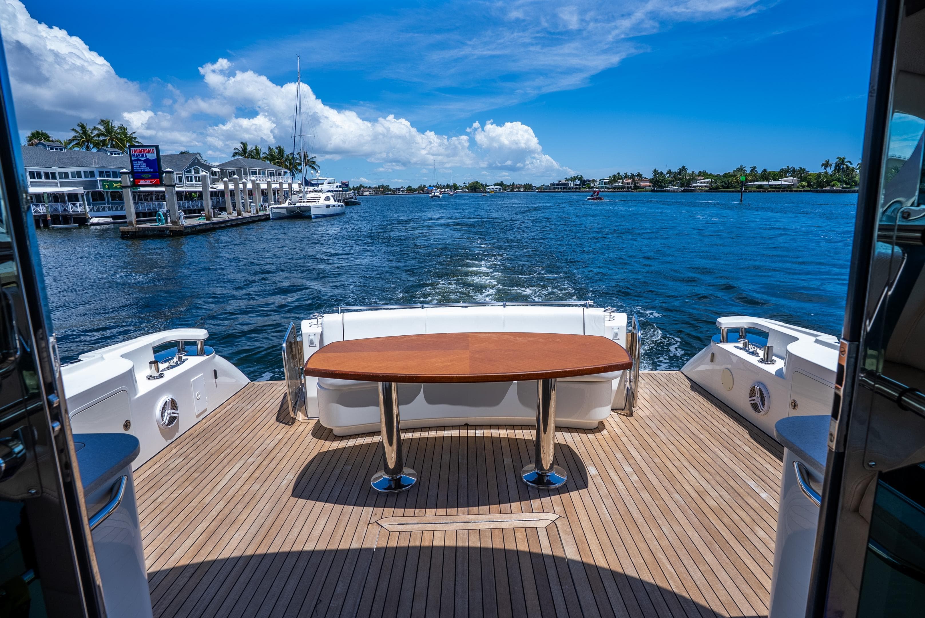 2008 Sea Ray 60 Sundancer yacht deck with wooden table, overlooking marina and blue waters.