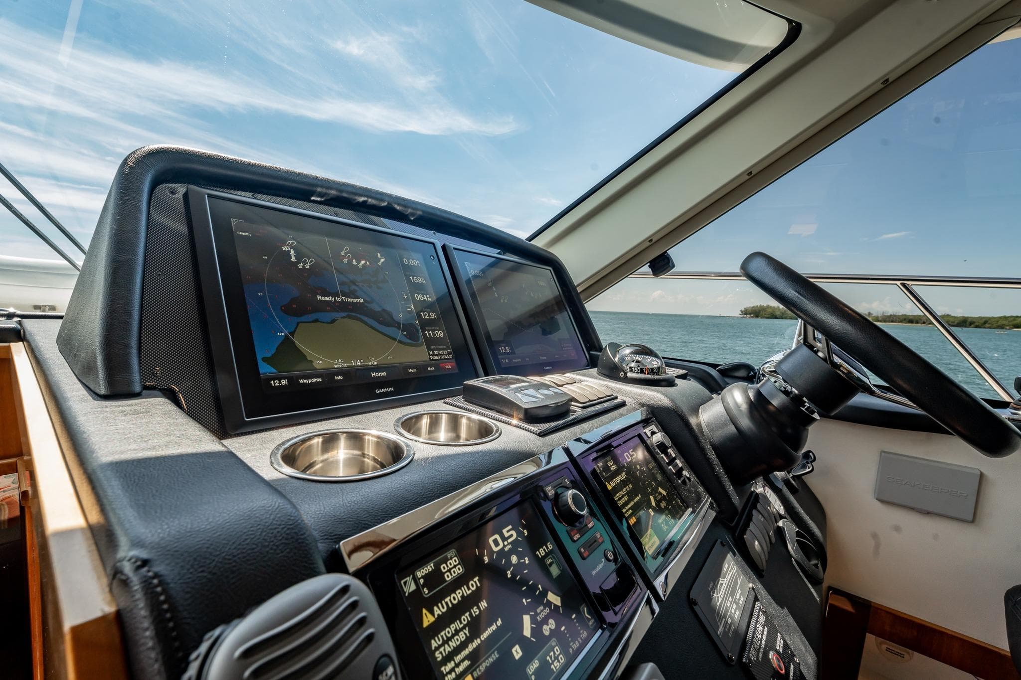 Helm of 2016 Riviera 5000 Sport Yacht with navigation screens and steering wheel.