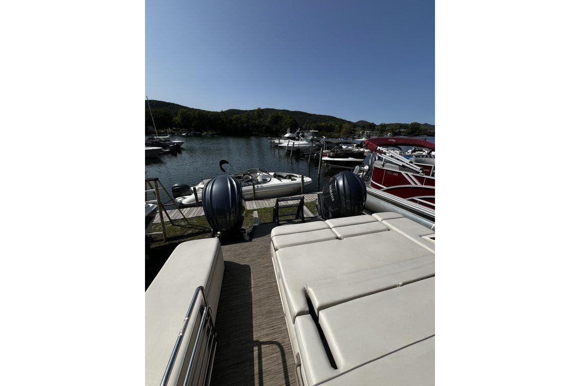 2021 Bennington 27 QXSBWA X2 pontoon boat docked at a scenic lakeside marina.