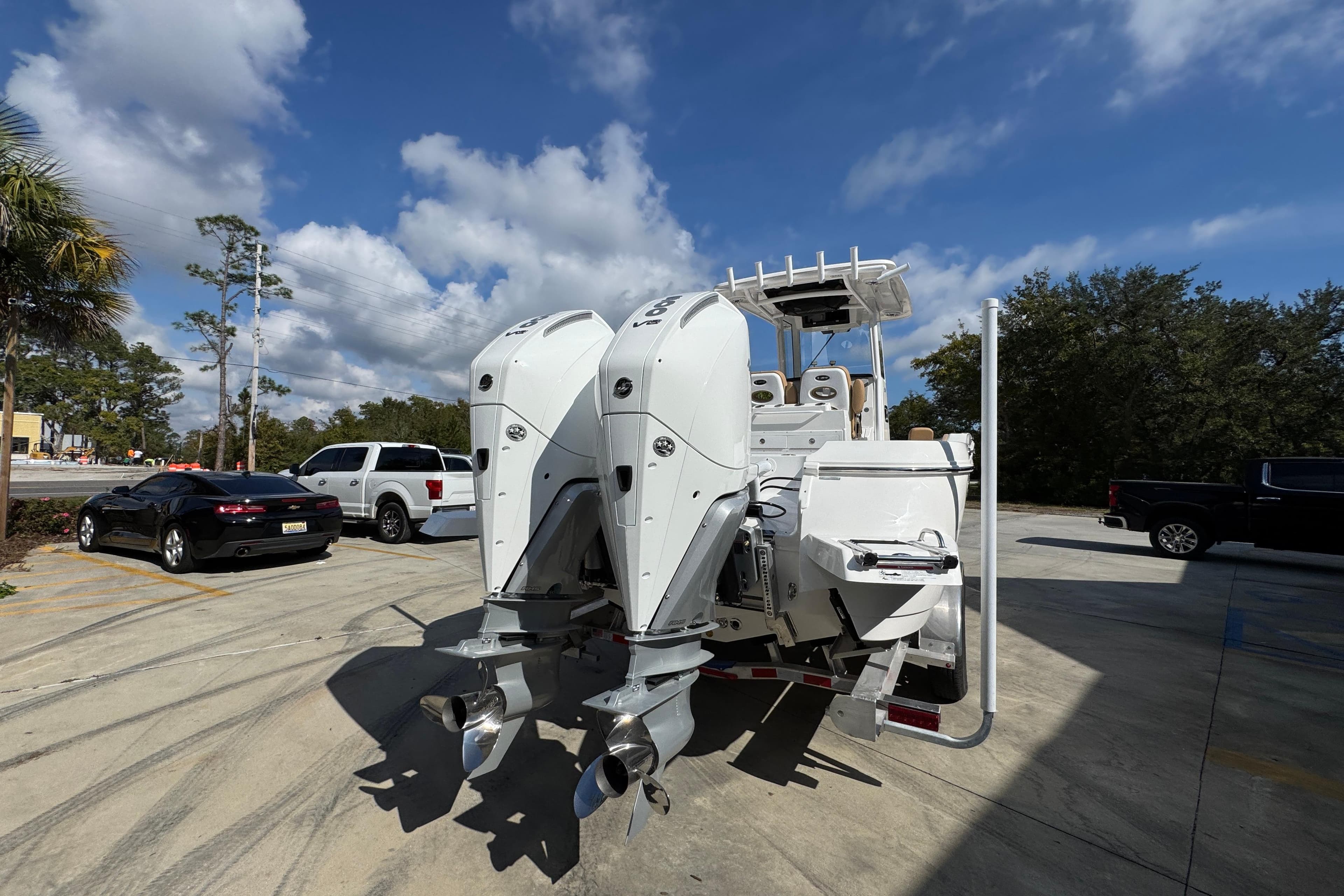2026 Caymas 291 boat with dual outboard motors in a parking lot under a blue sky.