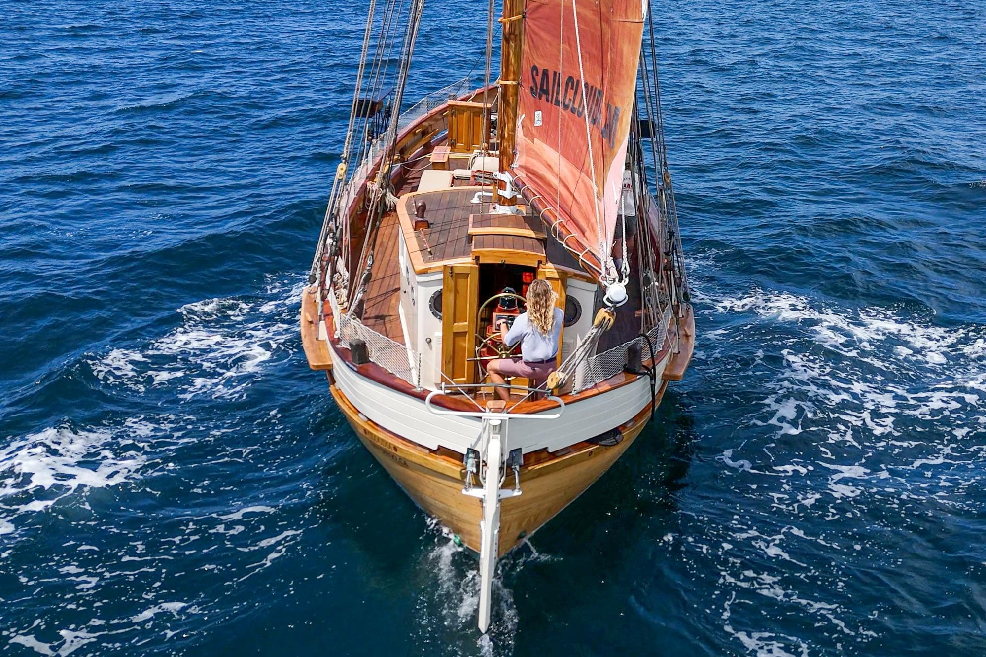 1938 Norwegian Double Ended Ketch sailing on open sea with vibrant red sails.