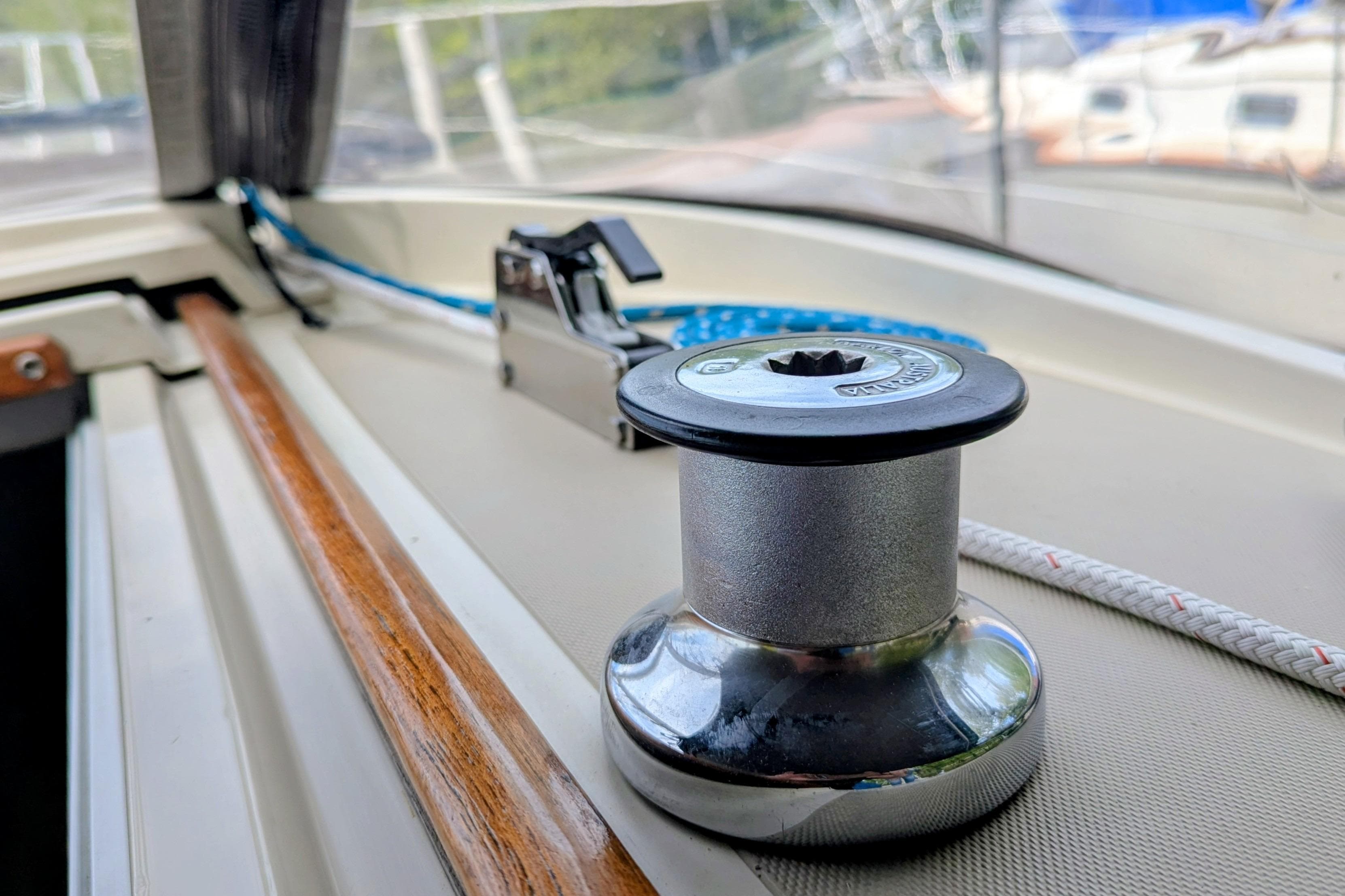 Winch and cleat on 1985 O'Day 35 sailboat deck, with ropes and wood trim.