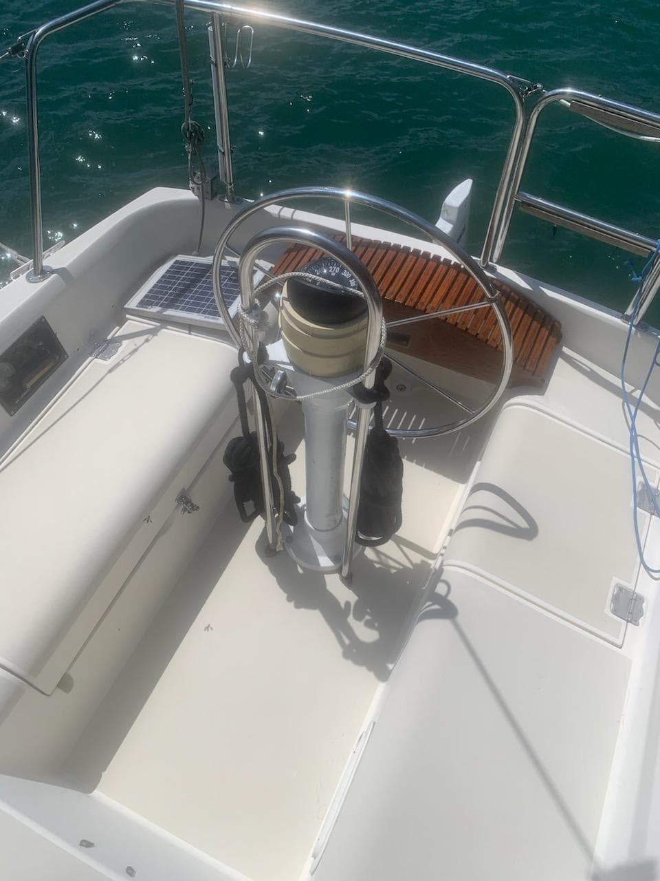 Steering wheel of a 1990 Pearson 27 sailboat on a sunny day.