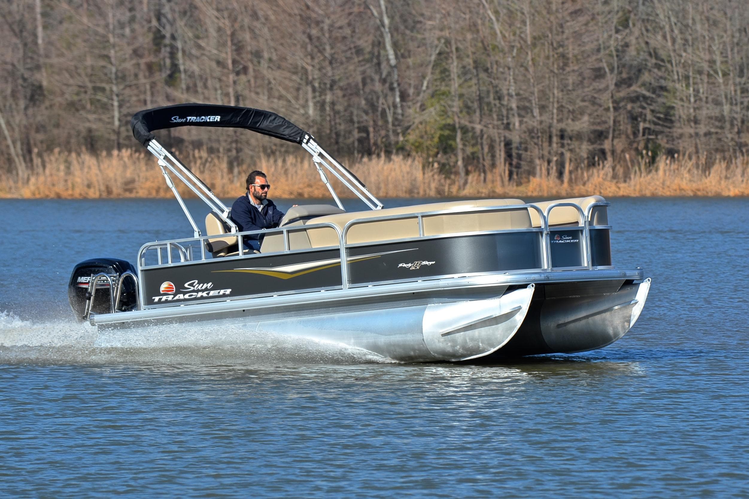 2025 Sun Tracker Party Barge 18 DLX pontoon boat cruising on a lake.