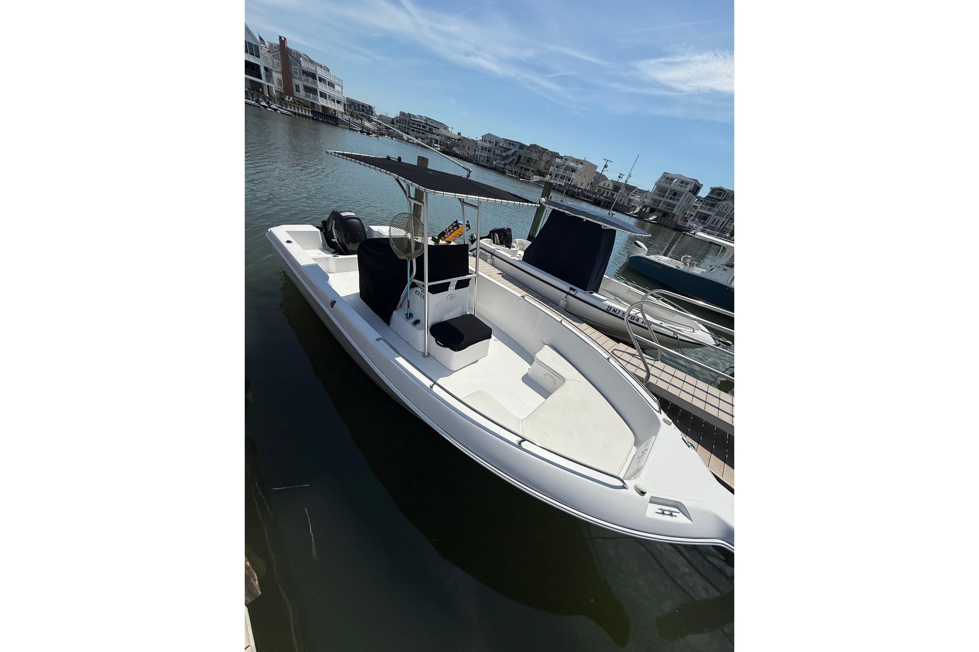 2013 Pro-Line 23 Sport boat docked in a marina, featuring a sleek design and T-top.