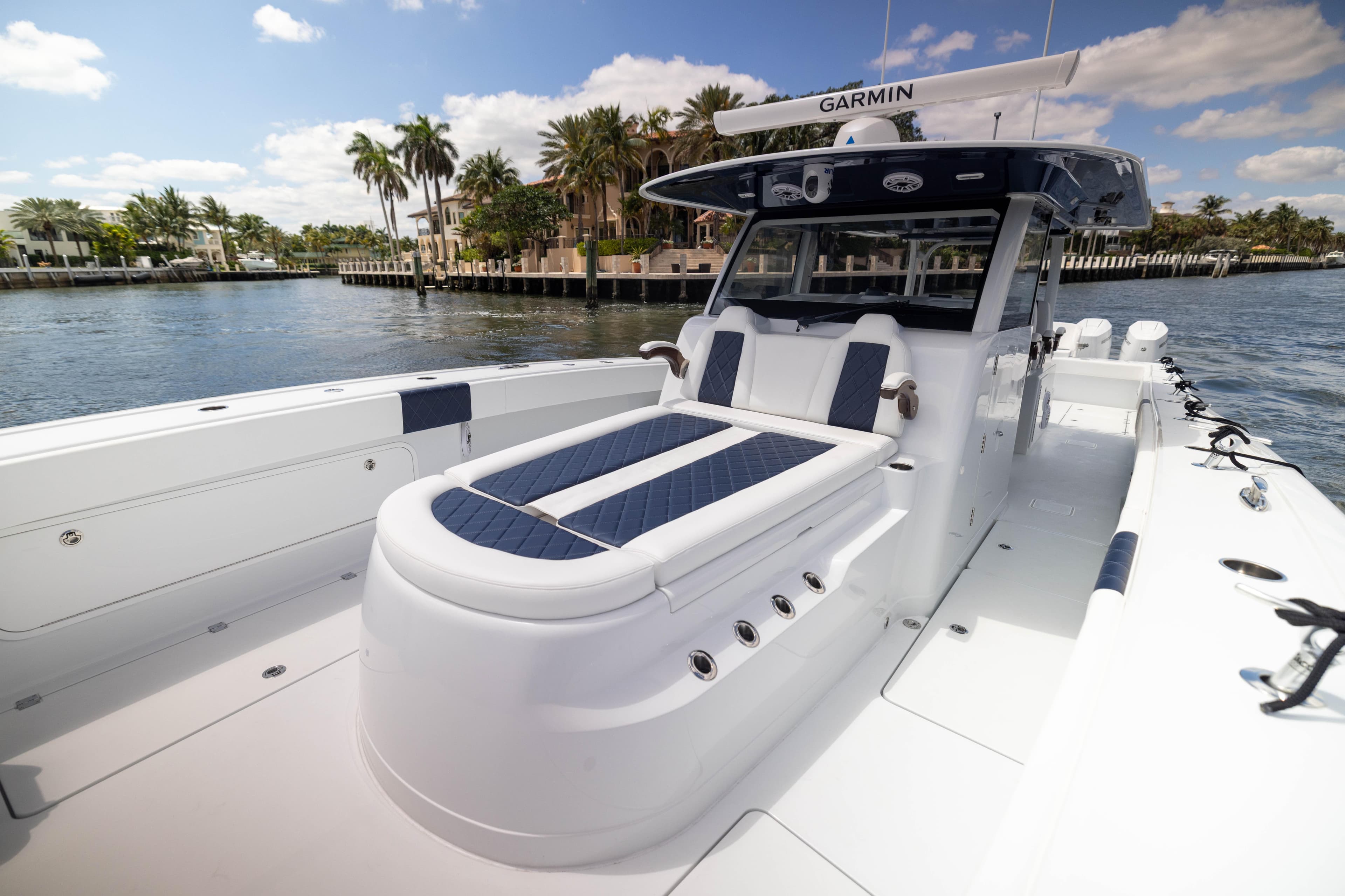 2026 Freeman 47 LX boat with luxurious seating, docked near palm trees and waterfront homes.