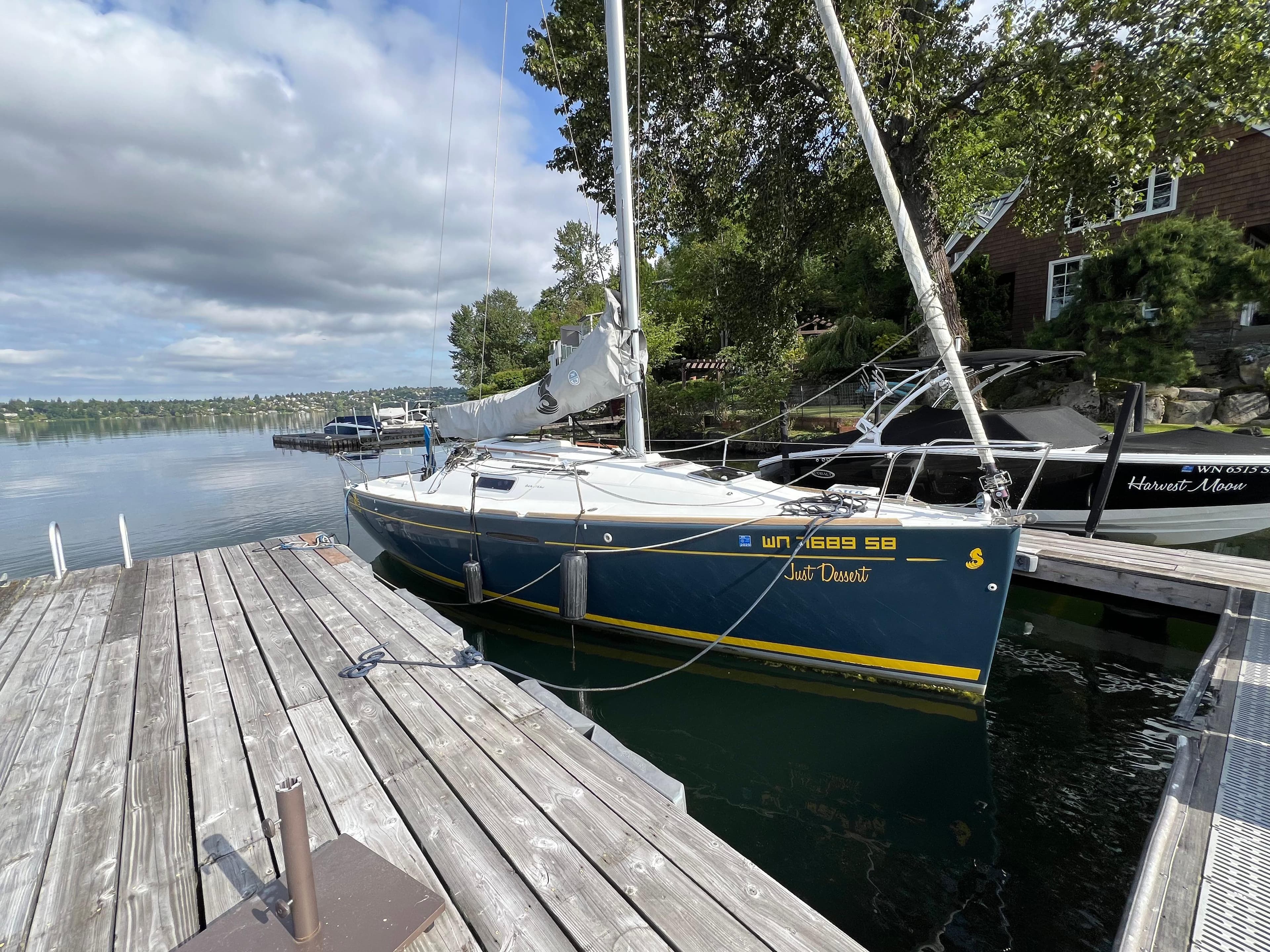 2014 Beneteau FIRST 25 S sailboat docked by a wooden pier on a calm lake.