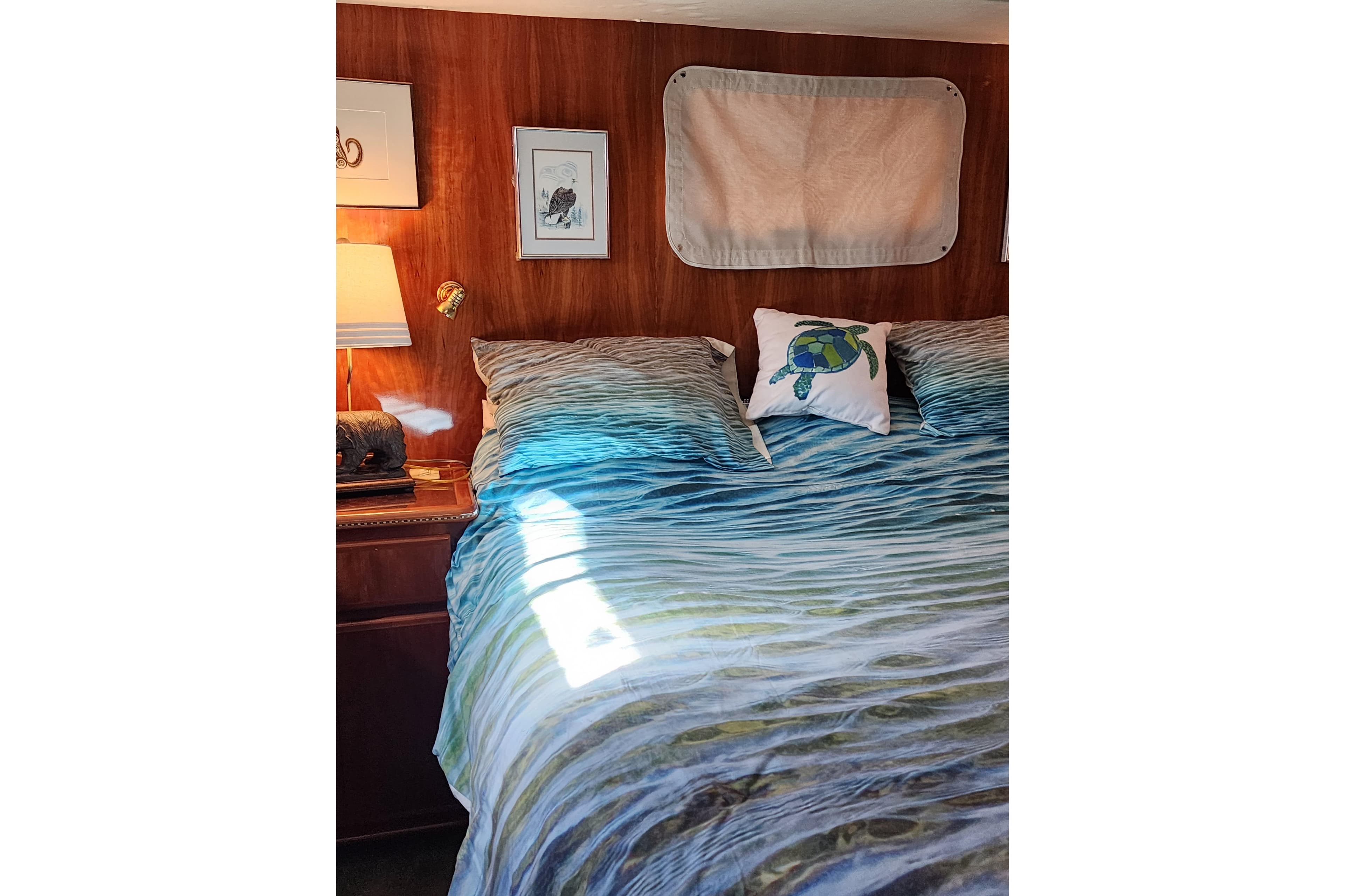 Cozy bedroom in 2000 Novatec Cockpit Motor Yacht with ocean-themed bedding and turtle pillow.