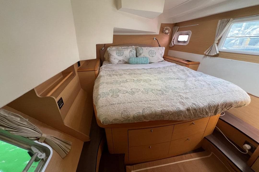 Cozy bedroom interior of 2012 Lagoon 500 yacht with double bed and wooden cabinetry.